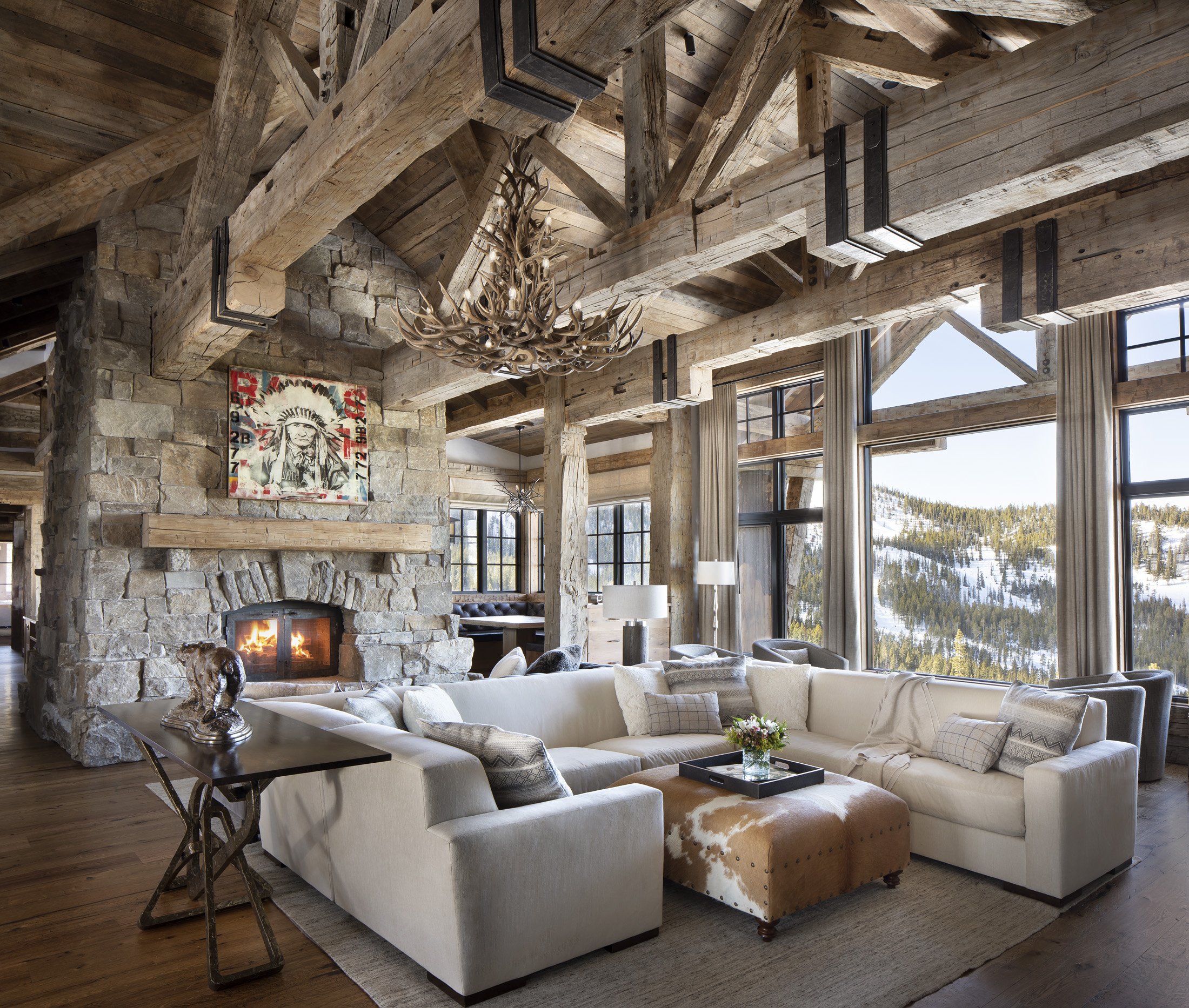  Open living space with heavy timber framing and stone fireplace at ski home in Big Sky Montana