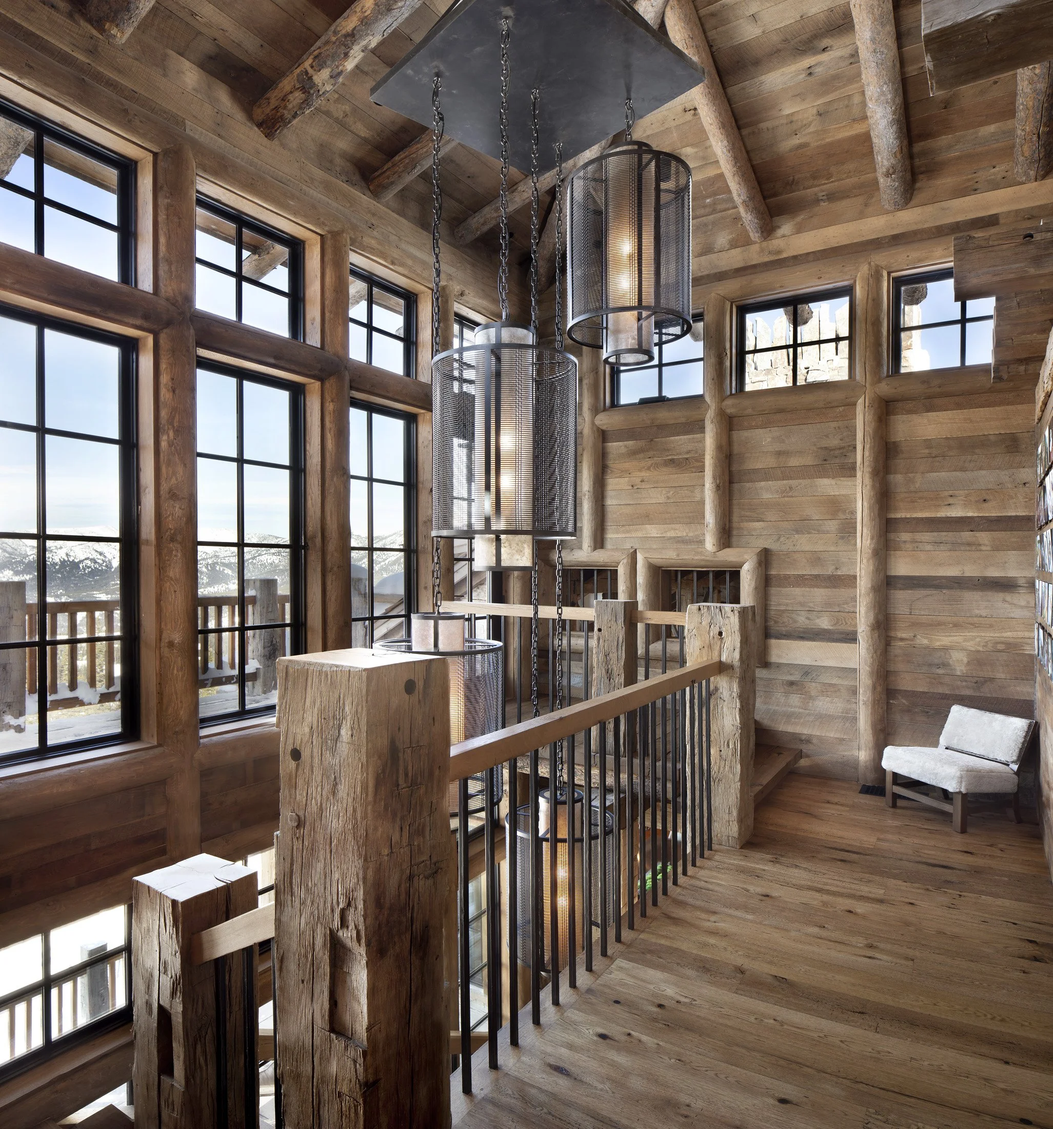 Stair hall with heavy timber posts, wood walls, and hanging light fixtures