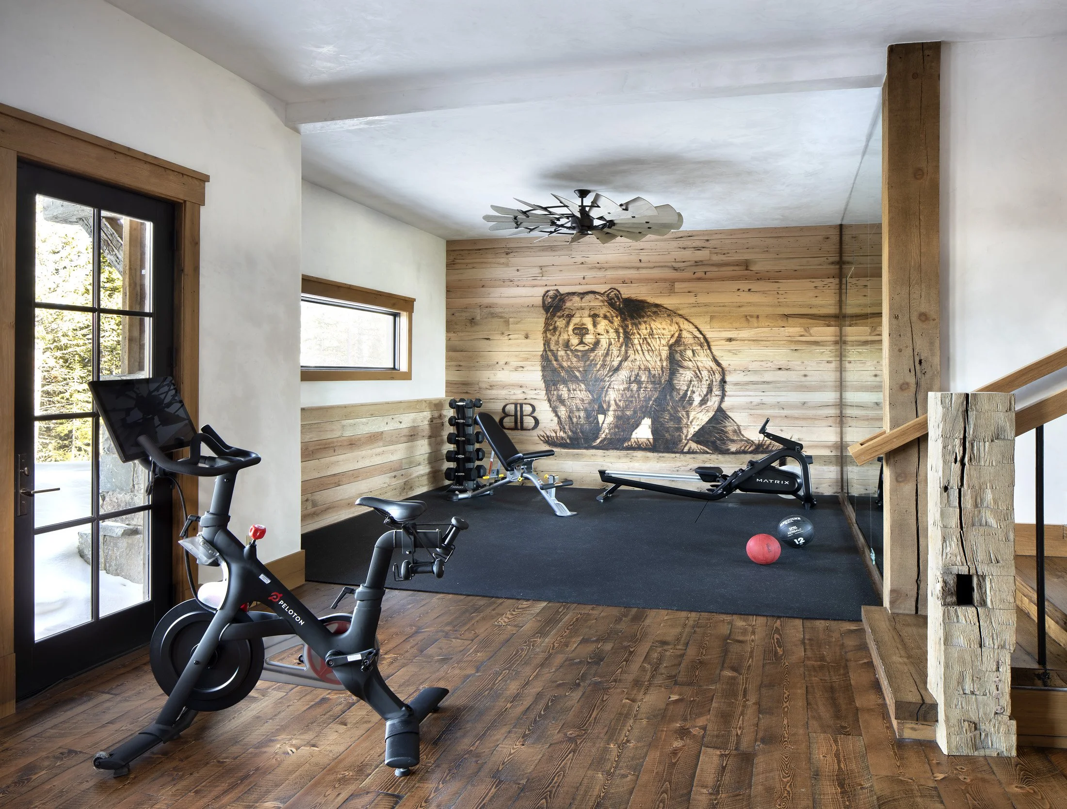Home gym with wood walls, exercise equipment, and bear artwork