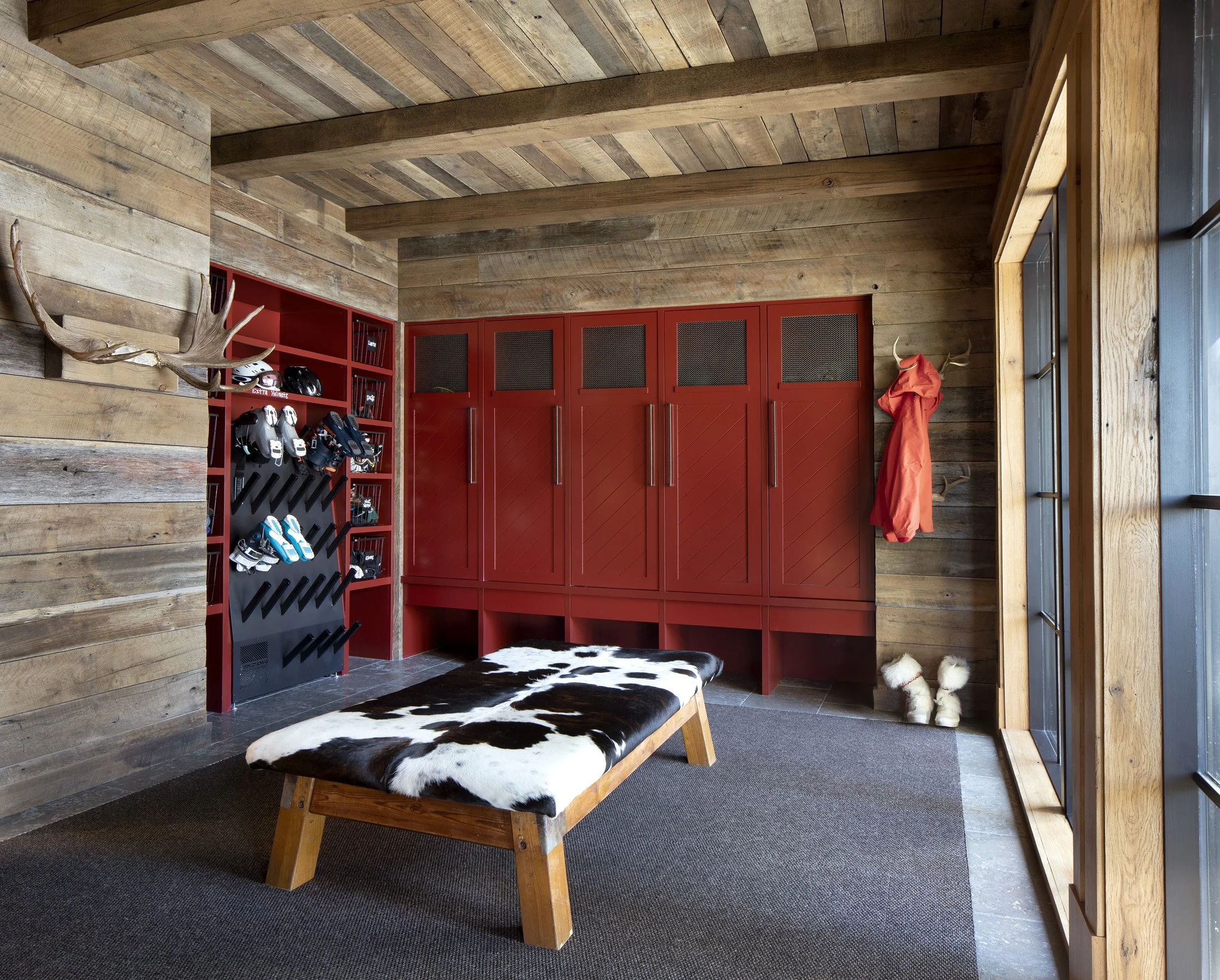 Ski room with red lockers, gear storage, and bench seating in mountain home in Big Sky, MOntana
