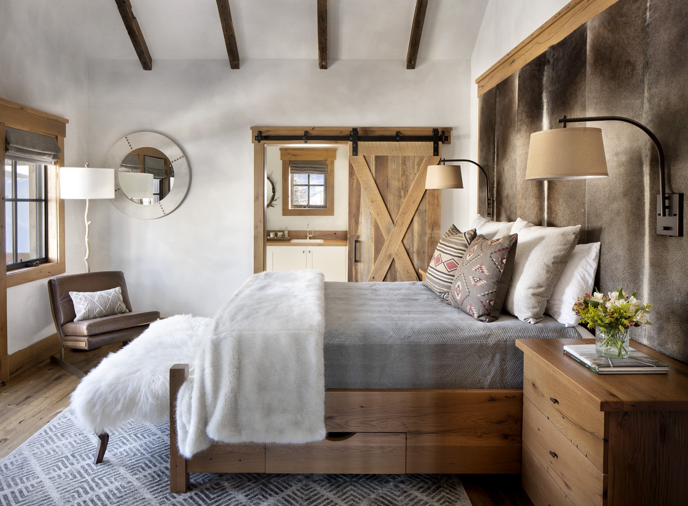 Bedroom with timber ceiling, wood furniture, and natural light in Big Sky Montana home