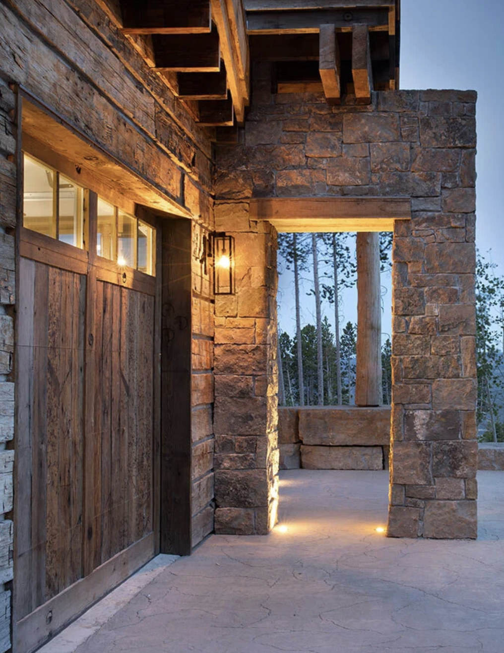 Reclaimed wood garage door with natural stone walls and covered entry
