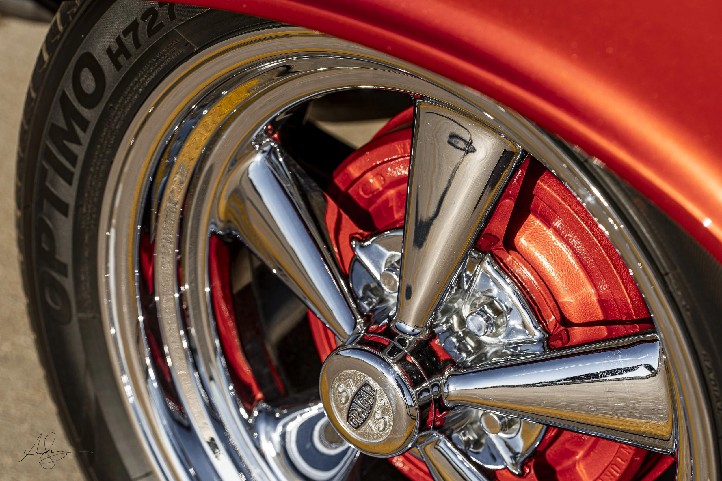Close-up of a shiny chrome car wheel with a red inner rim and a large disc brake caliper.