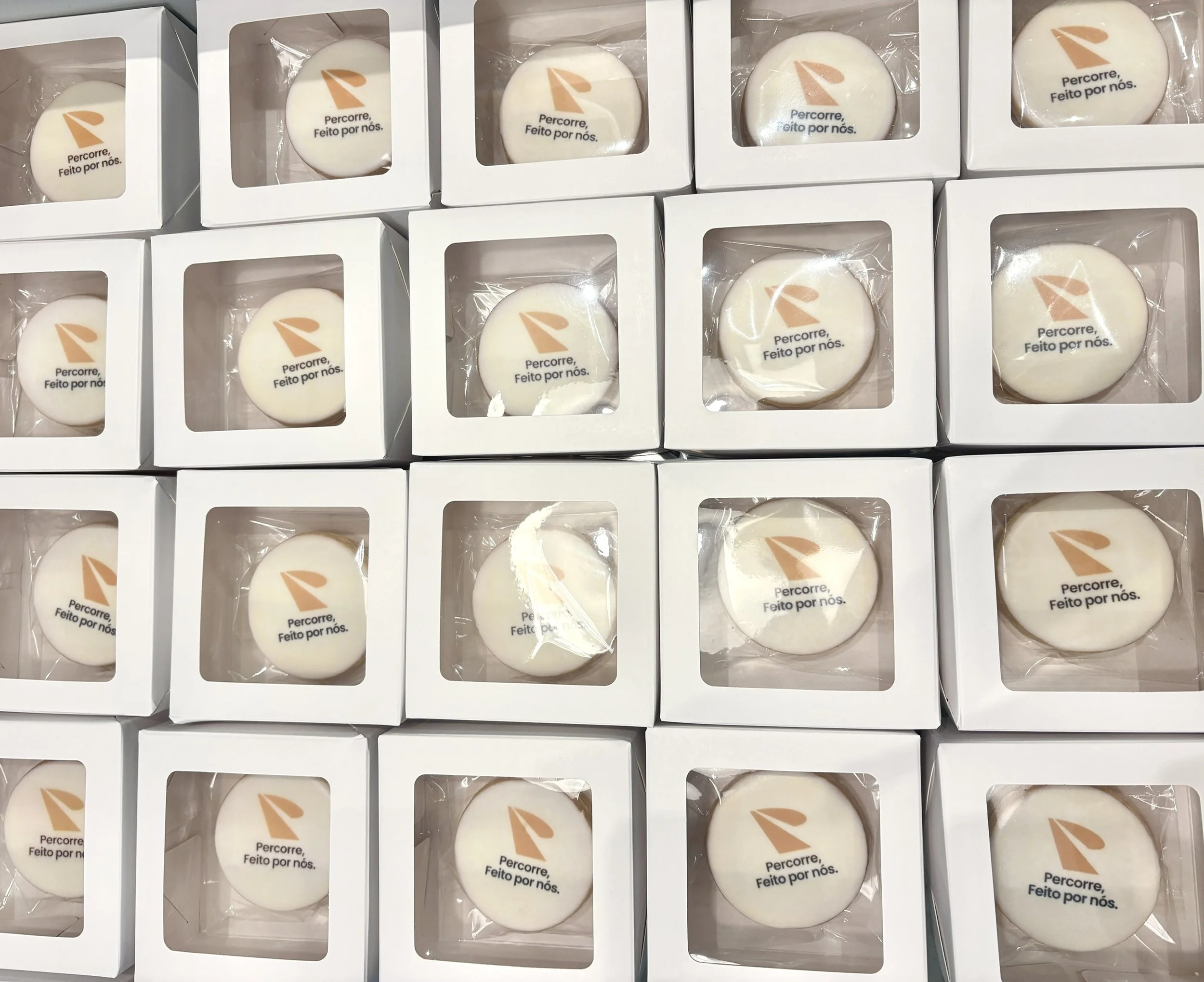 Vários biscoitos amanteigados decorados com logo de empresa para presentear clientes com slogan "Percorre, Feito por nós".