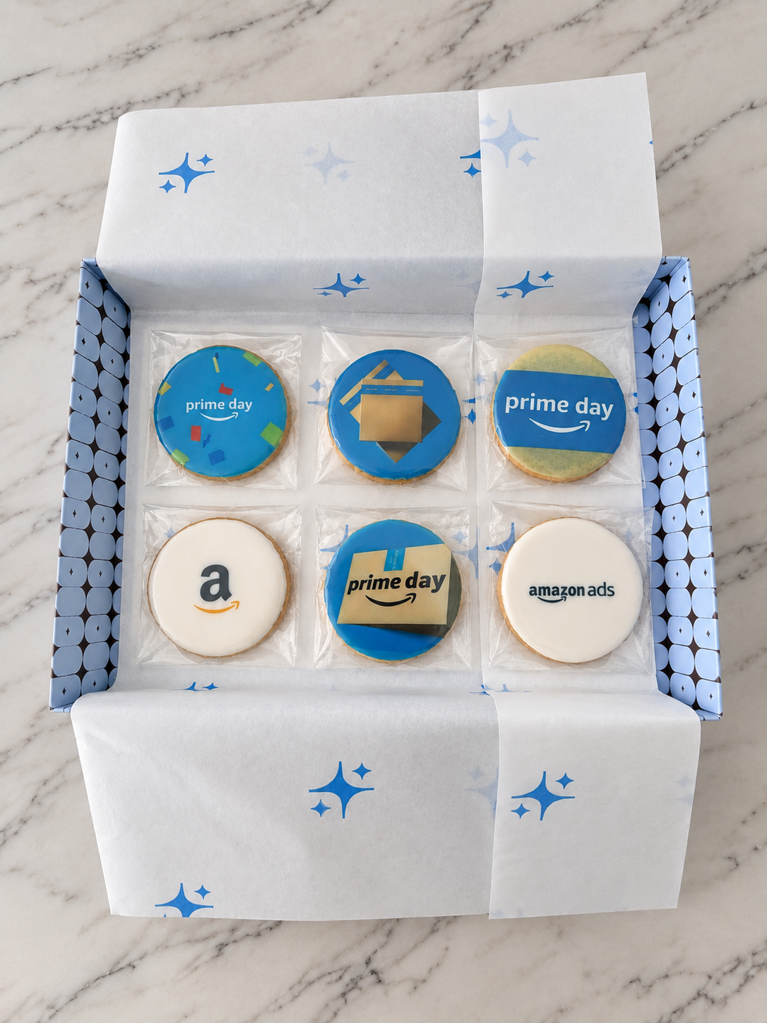 Caixa com seis biscoitos amanteigados decorados sob medida para empresa Amazon, cada um com temas relacionados ao evento Amazon Prime, como logotipos, o símbolo de Prime Day, e anúncios de Amazon.