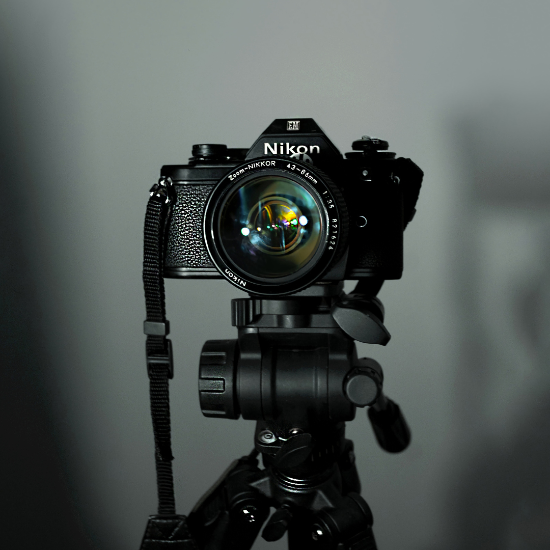 A Nikon camera mounted on a tripod, facing forward against a plain background.