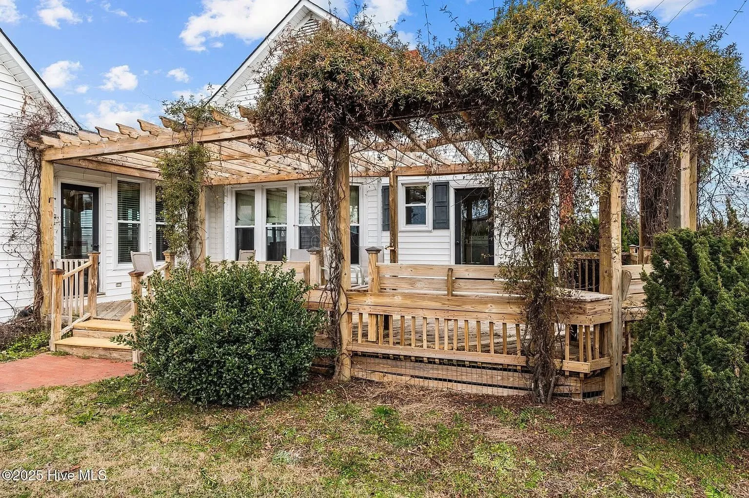 Photo of the back porch at the house with a wooded terrace covered in vines and foliage and a black button saying apply now