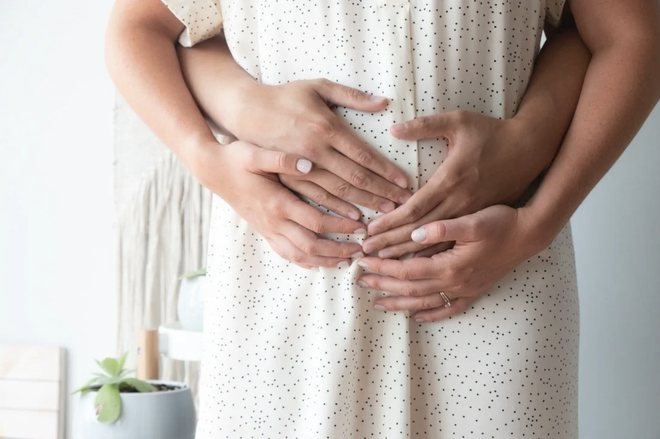 A pregnant woman in a white polka dot dress holding her stomach — representing the hope, vulnerability, and emotional support needed during the perinatal journey — Attune Therapy Group, Washington State