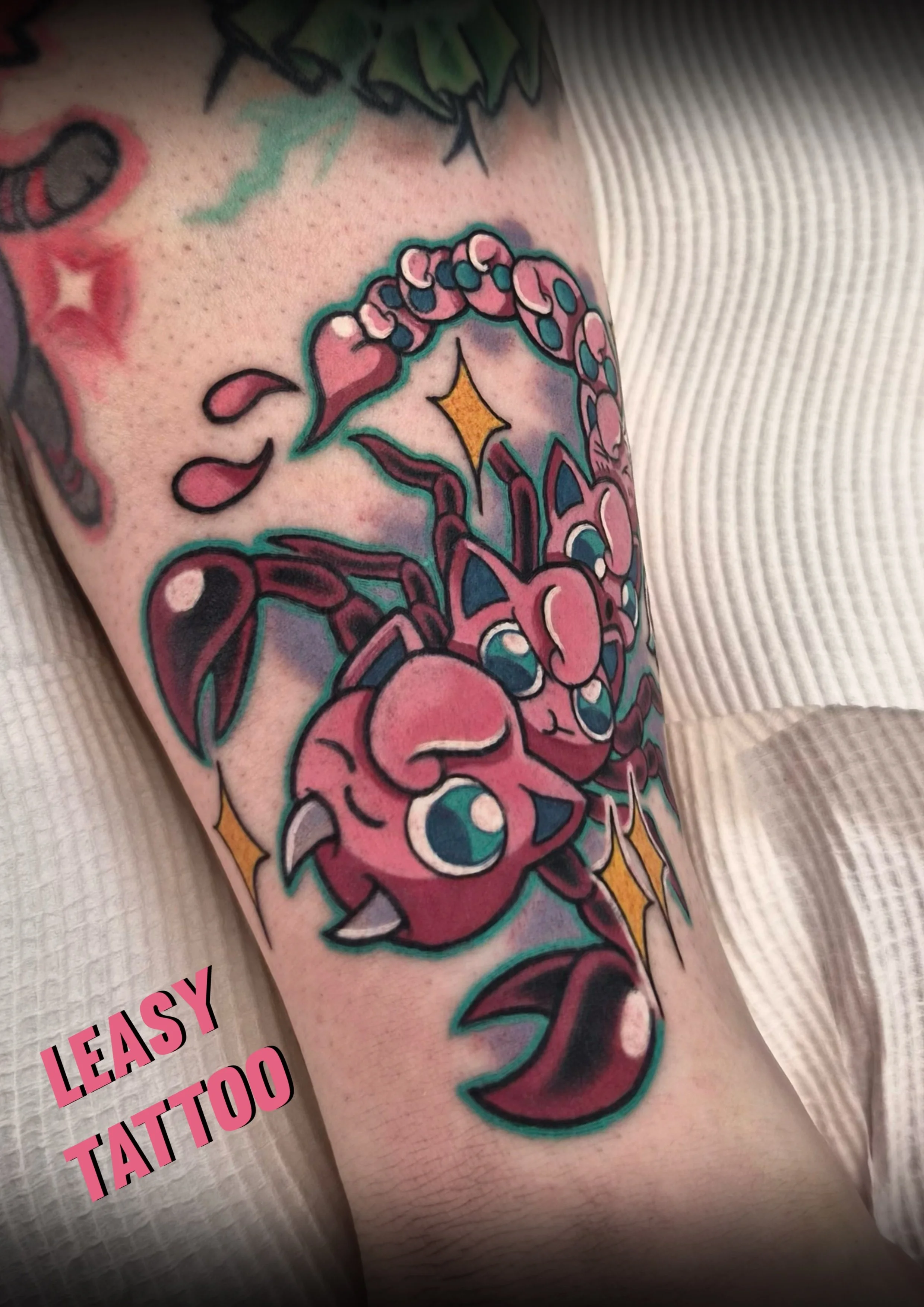 A colorful tattoo of a pink octopus with large blue eyes on a person's arm, with a star and other elements in the background.