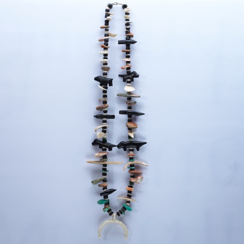Necklace made of various beads and charms, including small animal or shell pieces, with a crescent-shaped pendant at the bottom.