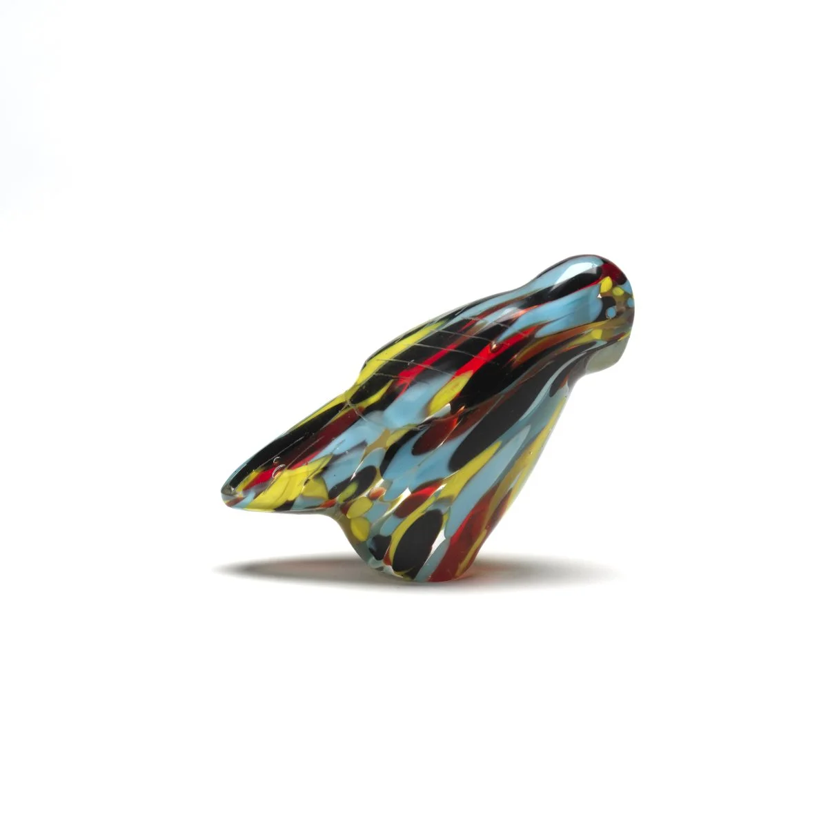 Colorful glass art sculpture with abstract swirls of red, yellow, black, and blue, set against a white background.