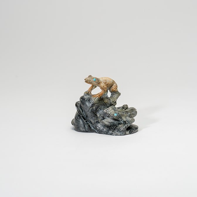 A small sculpture of a chameleon on top of a rock formation.