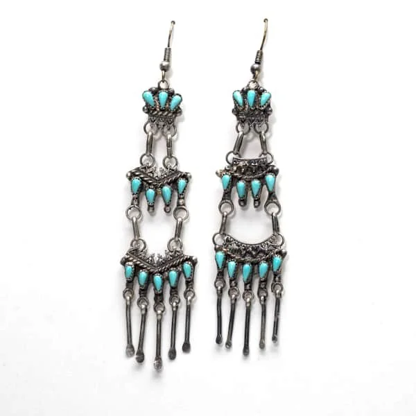Silver dangle earrings with turquoise stones arranged in three tiers, each with dangling silver bead accents.