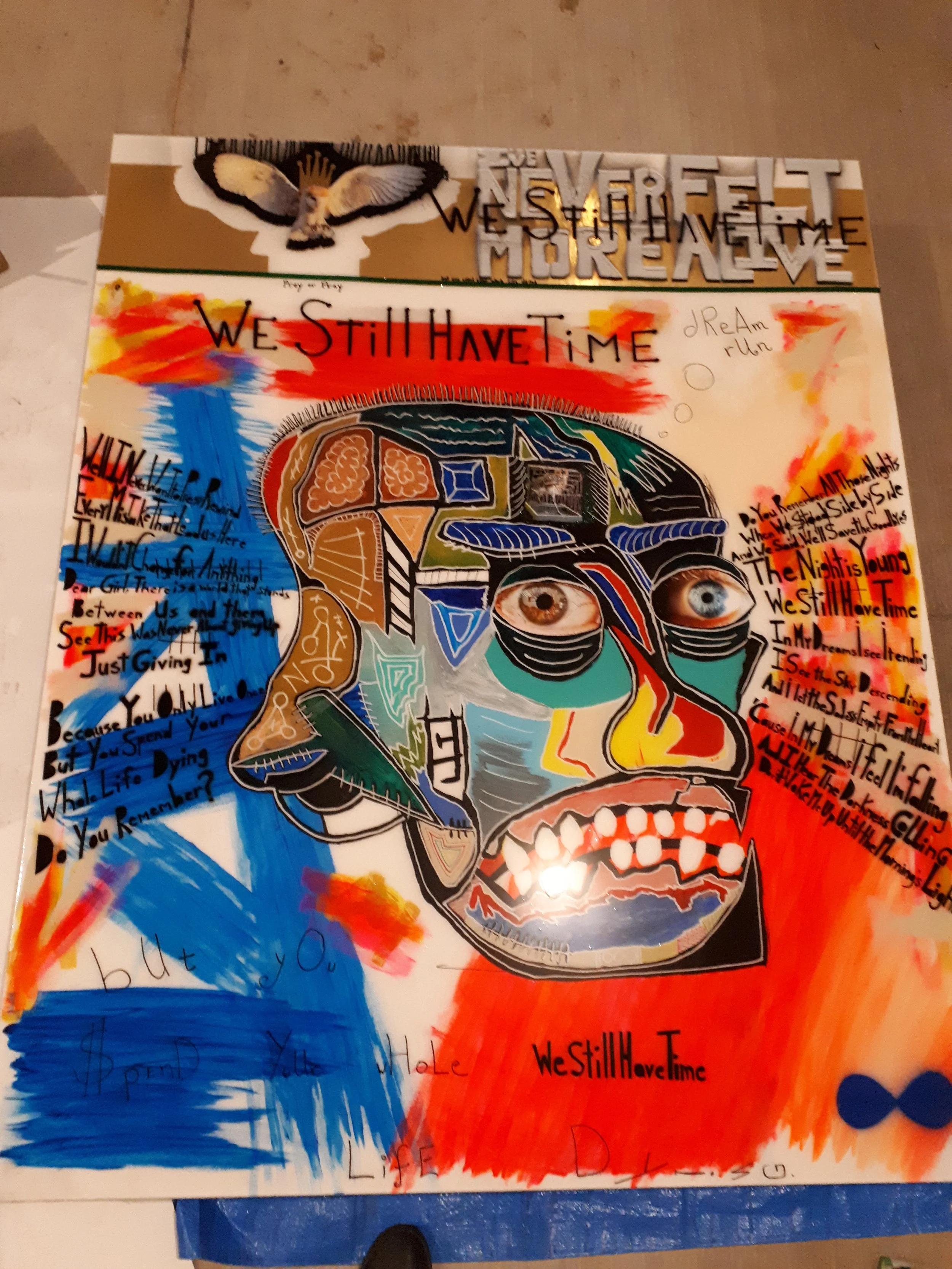 A colorful, abstract artwork featuring a human face with vivid colors and patterns, surrounded by handwritten text and doodles, with a large owl sticker at the top.