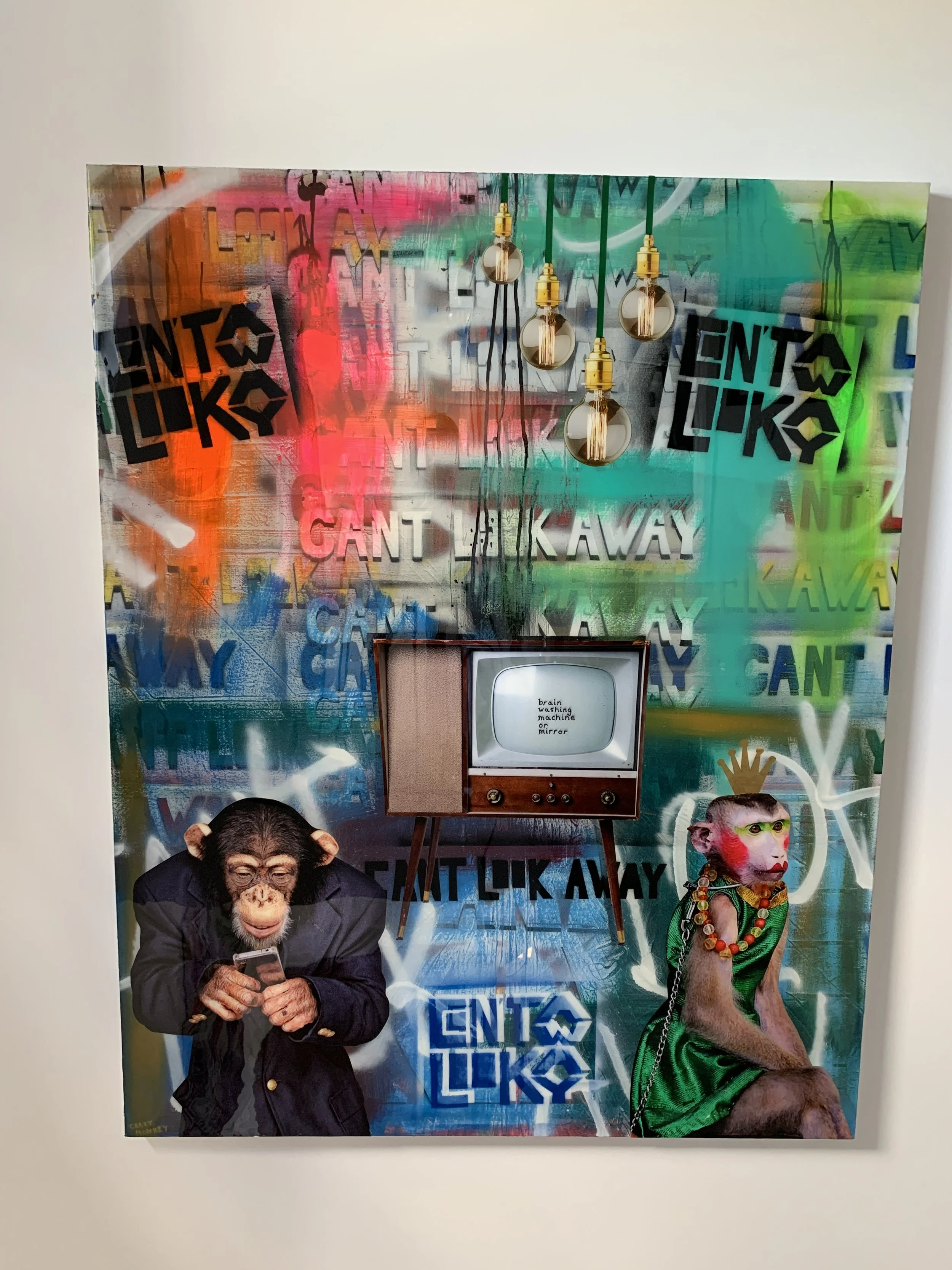 Mixed media art piece with graffiti background, featuring two anthropomorphic monkeys in costumes, one looking at a phone and the other sitting with a chain necklace, a vintage TV displaying 'brain washing machine or mirror,' and hanging light bulbs.