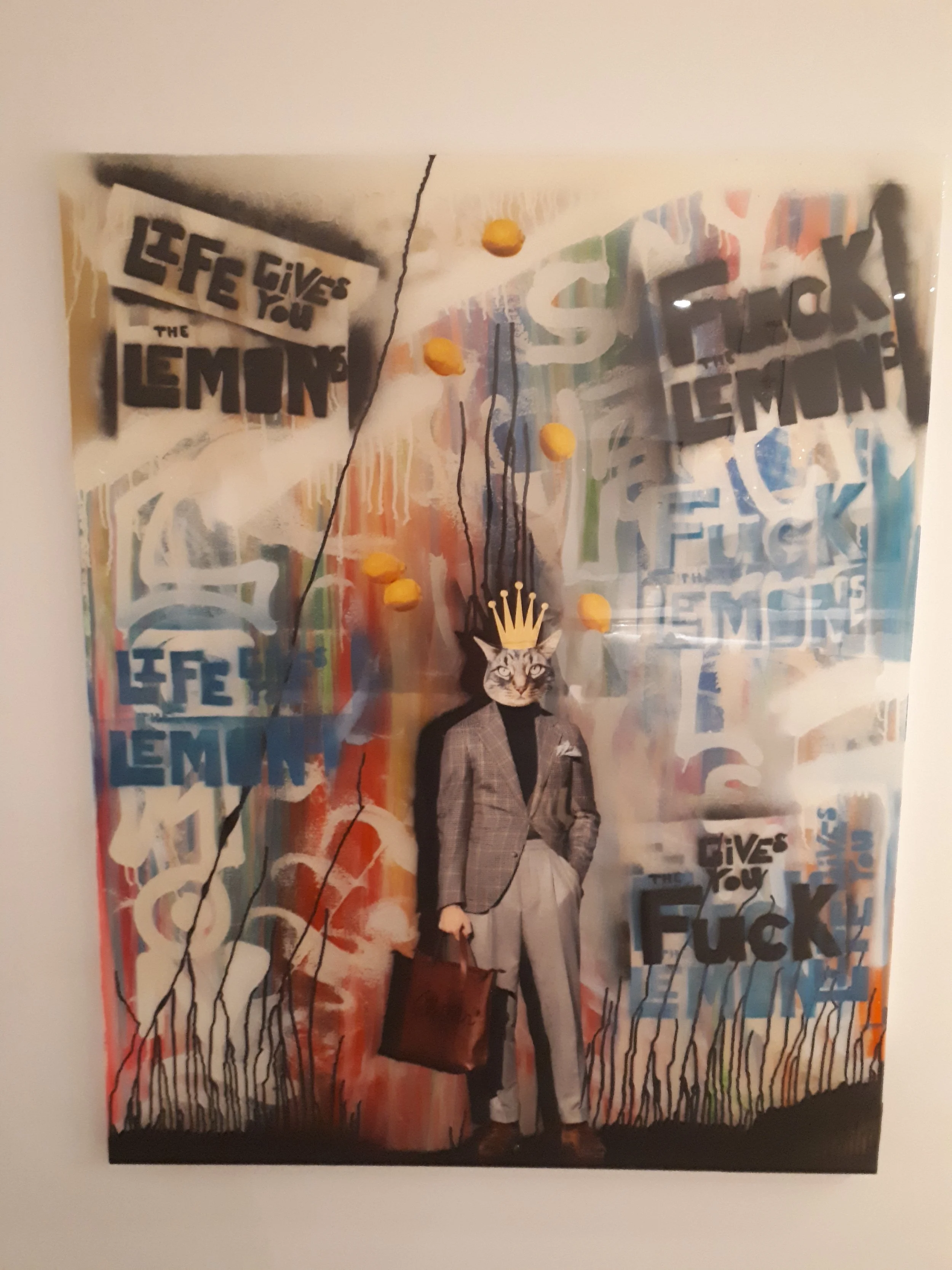 A mixed-media artwork featuring a human figure with a cat's face, wearing a suit and holding a briefcase, with a crown on its head, set against a colorful abstract background with graffiti-style text.