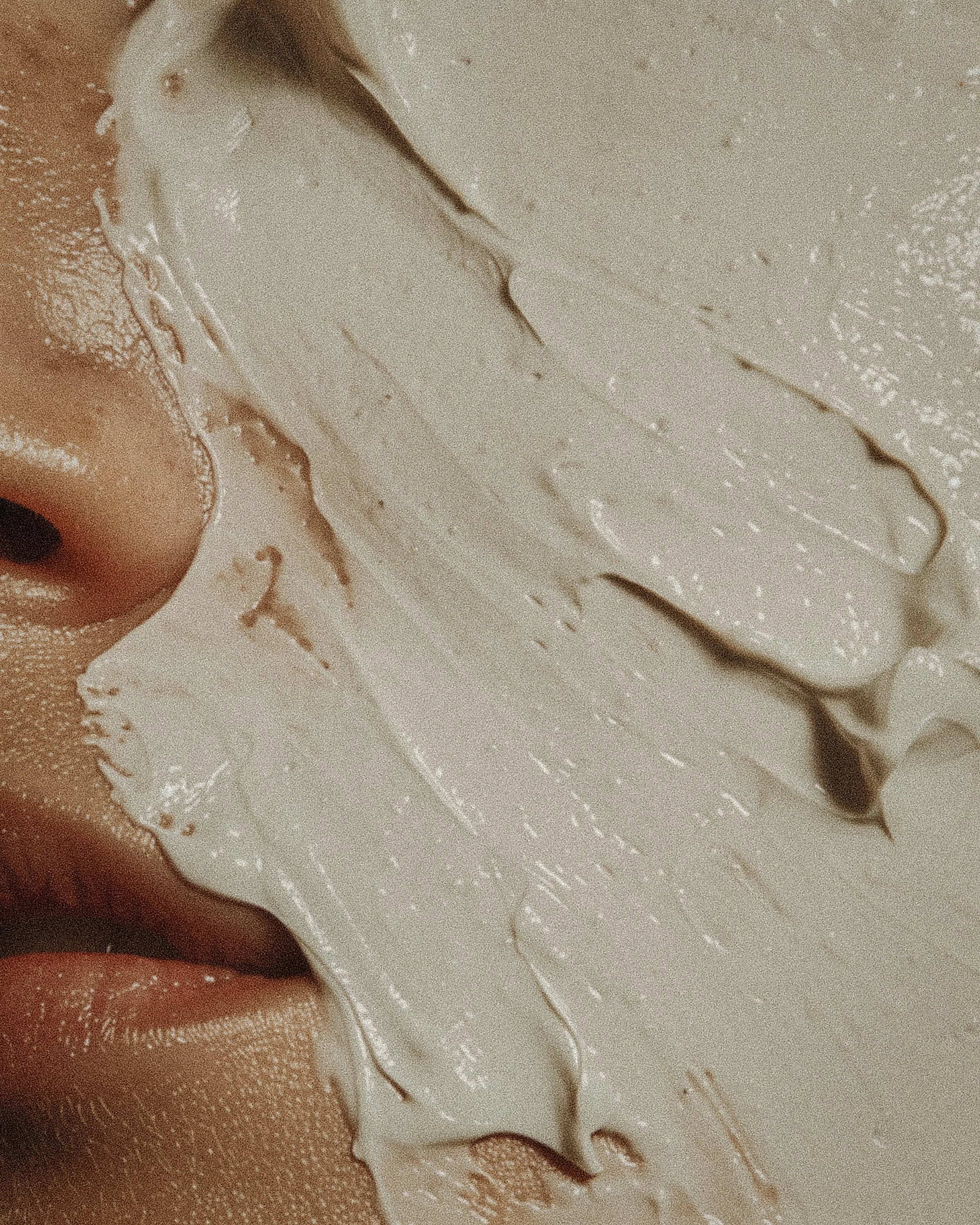 Close-up of a person's face with skin and eye makeup, featuring a shimmery, textured beige face with brown accents and a partially visible eye.