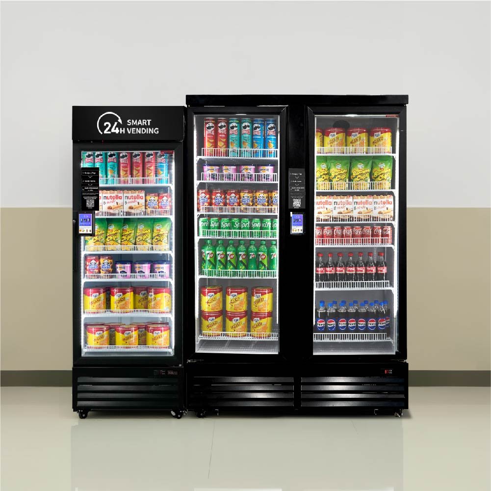 Three refrigerated vending machine smart coolers filled with various snacks and drinks, placed against a plain wall in a public setting.