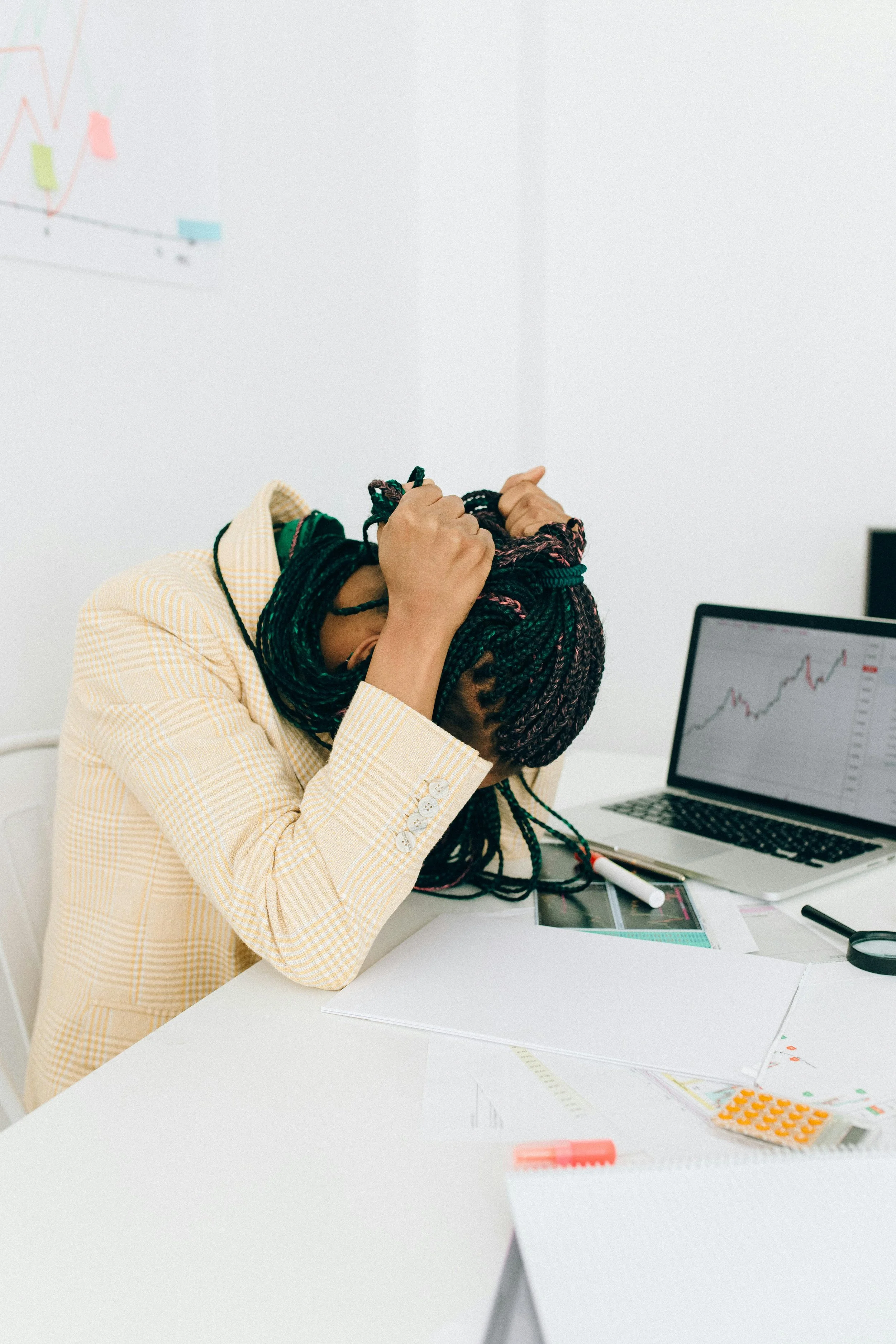 A stressed black woman sits at her work desk with a laptop. Dr. Mary Woodson can provide therapy to Wisconsin residents and UW students for burnout and stress.