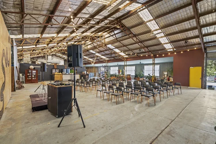 Empty event space in an industrial-style venue with chairs arranged in rows for a presentation or meeting.