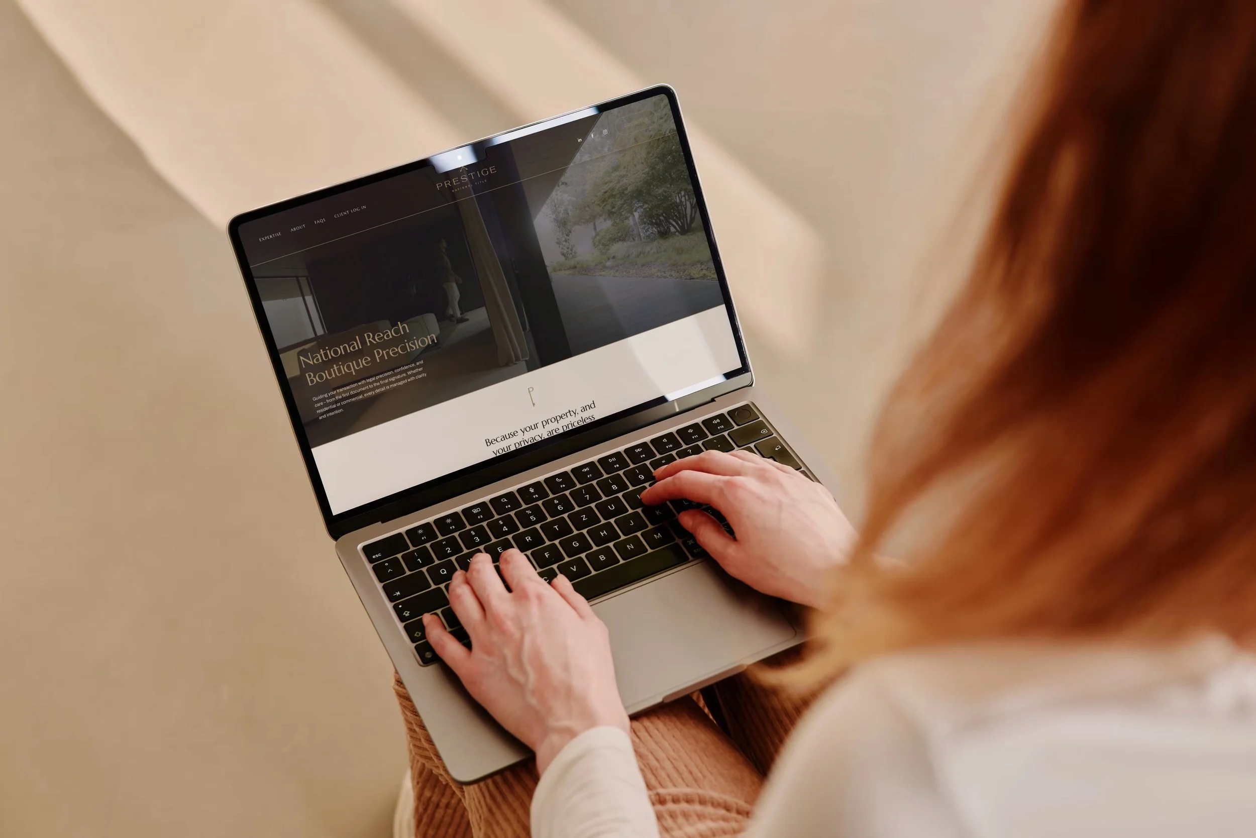 A woman typing on the computer with a display of Prestige National Title website