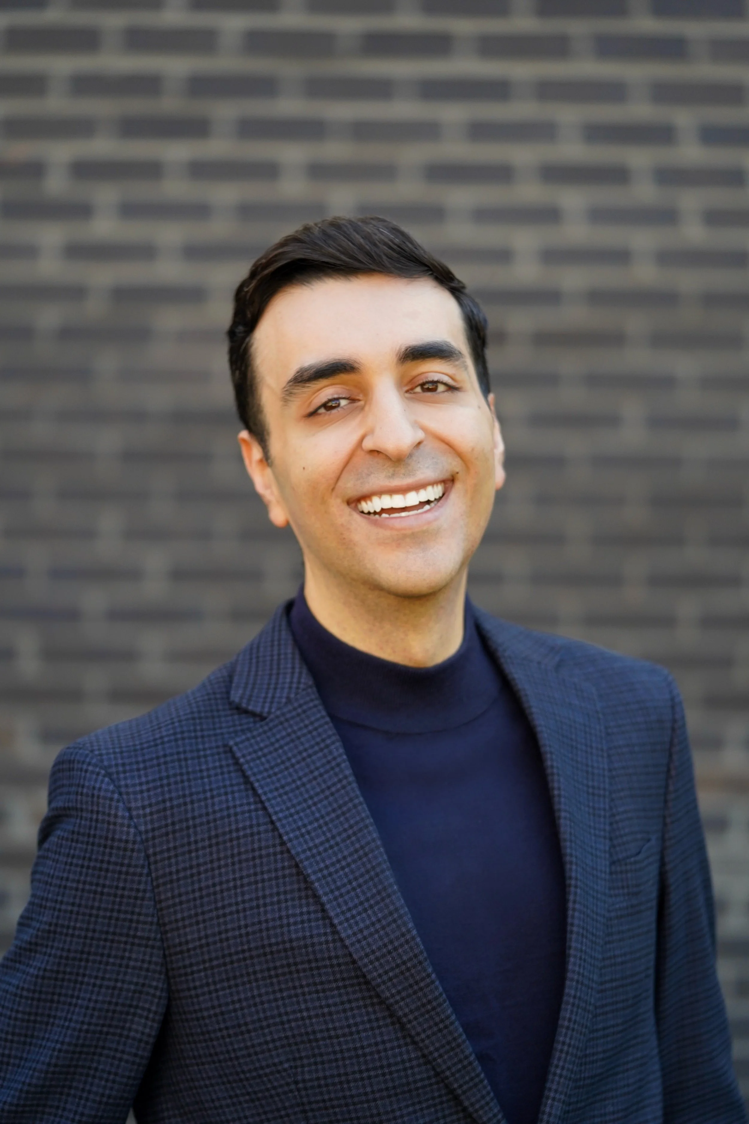 Doctor Daniel Yanes standing in front of a brick wall