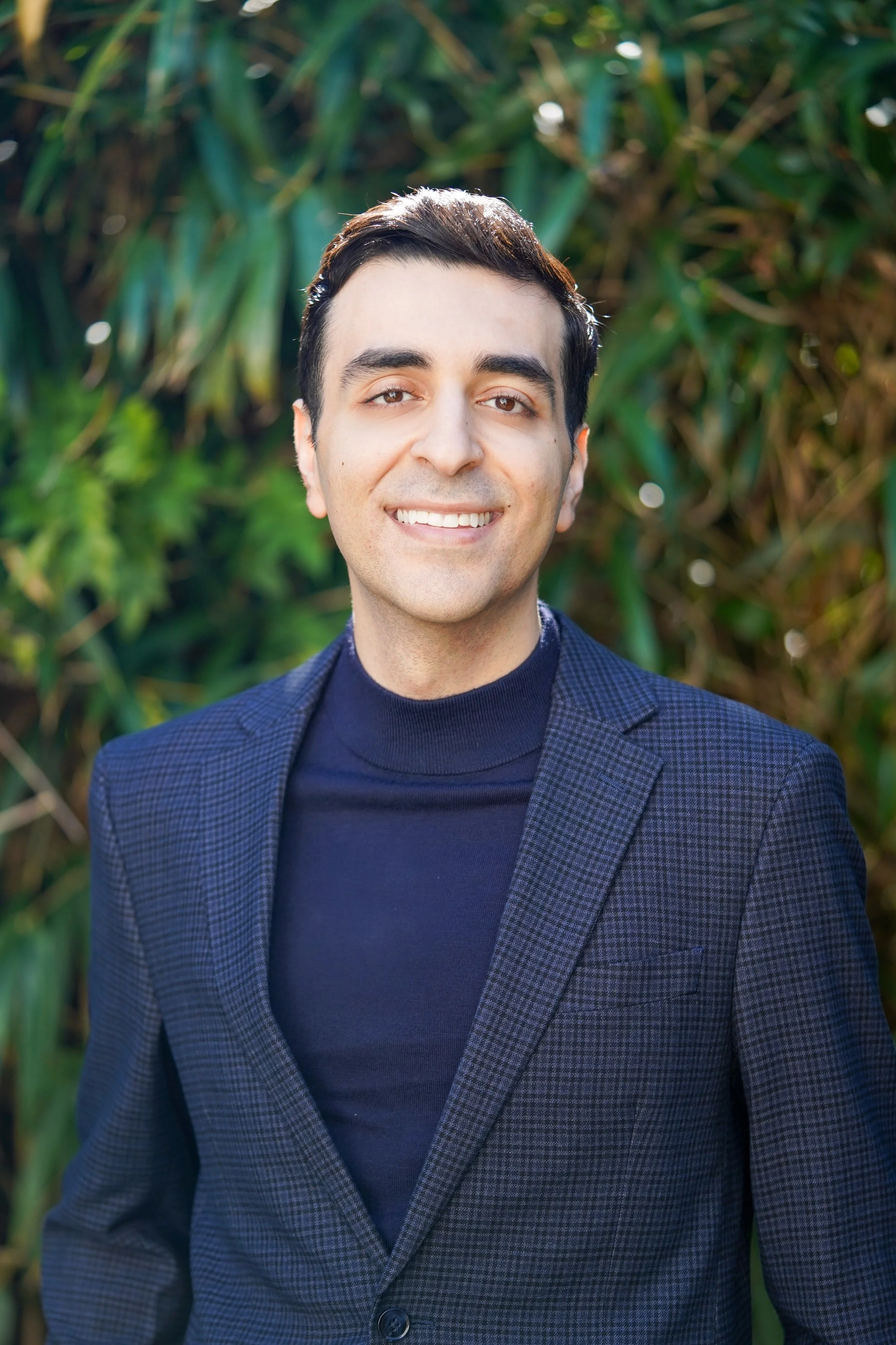 Dr. Daniel Yanes standing in front of greenery