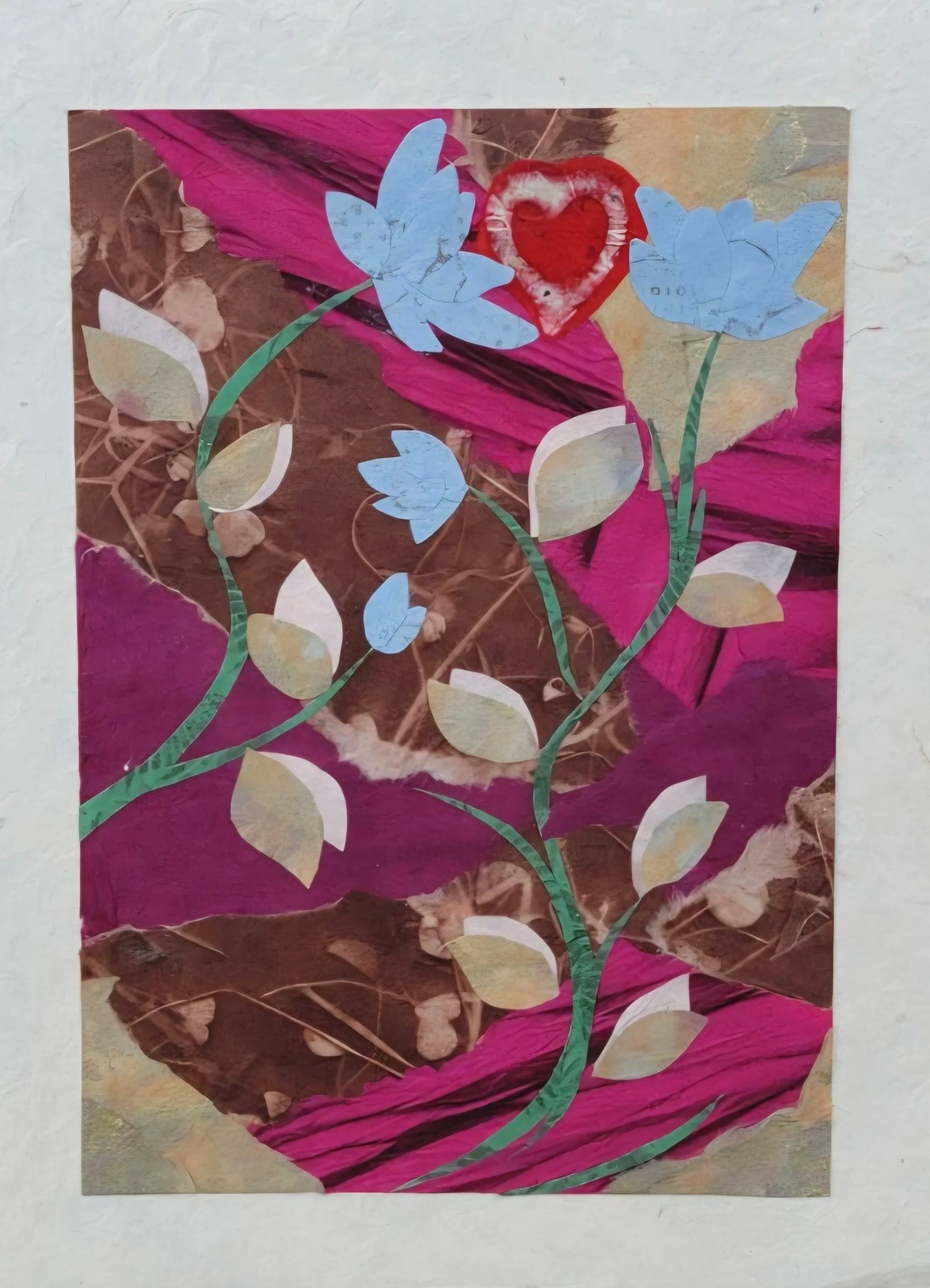 A collage artwork featuring a background of layered pink, brown, and beige paper with a floral design made from cut-out paper shapes of blue, beige, and green, forming a flower with two blue flowers, leaves, and a red heart in the center.