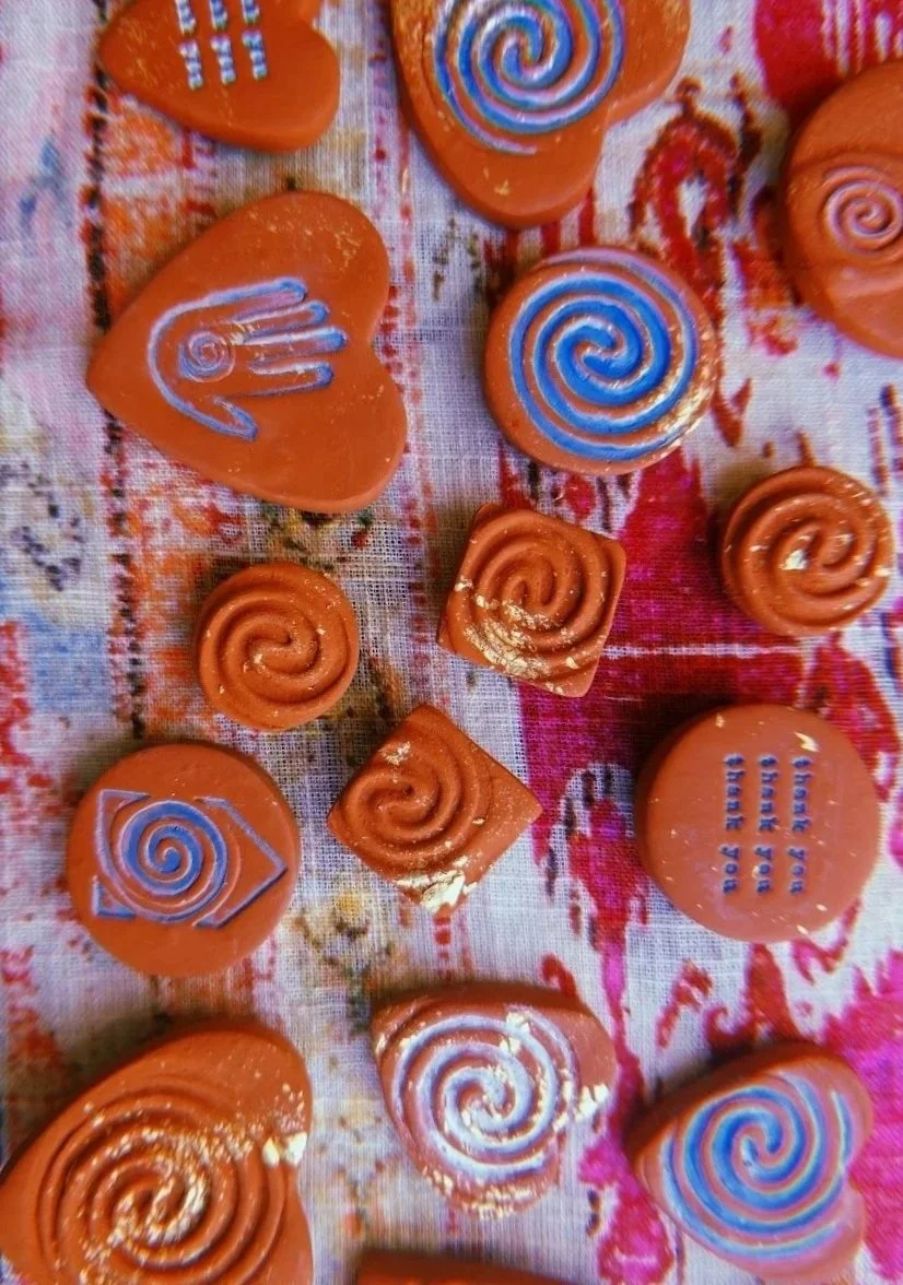 Small orange soap bars with spiral and striped designs on a fabric surface.