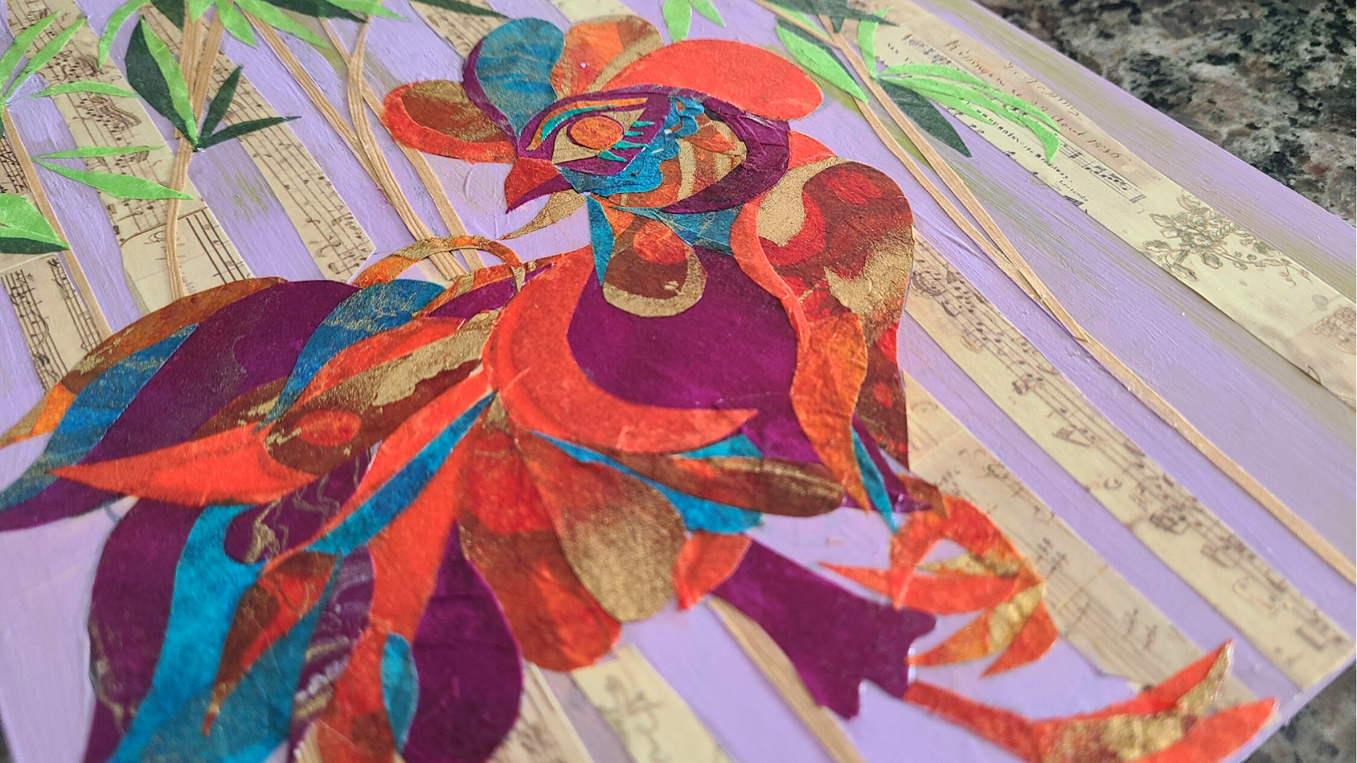 Close-up of a colorful collage art piece featuring floral designs with sheet music and purple painted background.