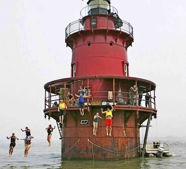 People jumping off Middle Ground Lighthouse and jumping into the water.