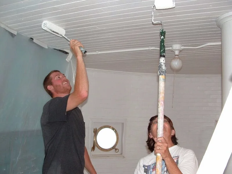 Two workers painting a ceiling with paint rollers on Middle Ground Lighthouse.