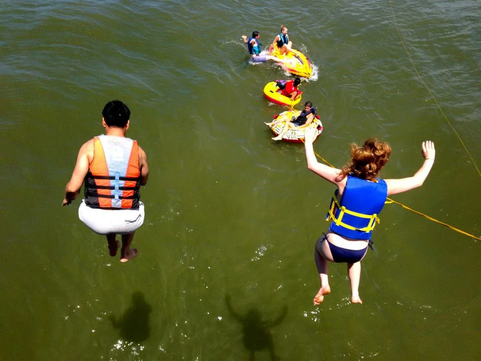 People enjoying a day at the water, jumping off of the side of Middle Ground Lighthouse. 