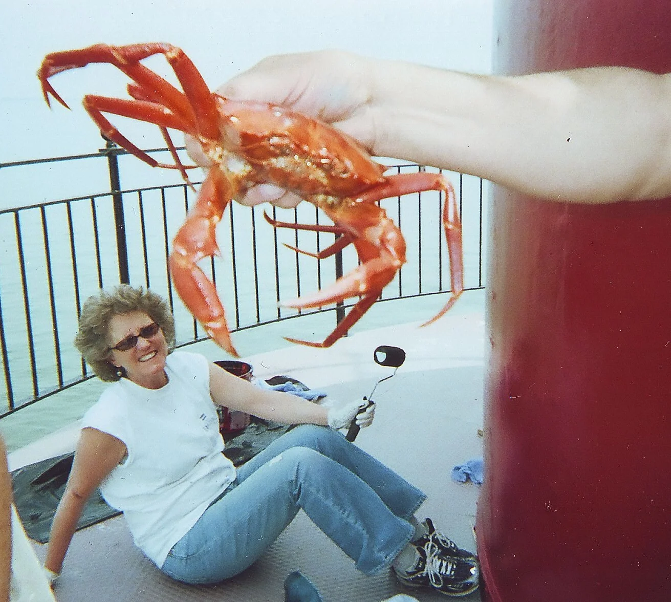 Large Chesapeake Bay crab being held up in front of a woman sitting on the watch level deck of Middle Ground Lighthouse.