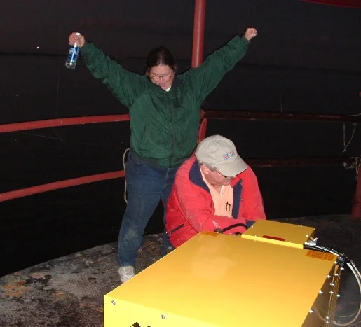 Workers celebrating getting the large, yellow generator onto the main deck of Middle Ground Lighthouse from the boat. 