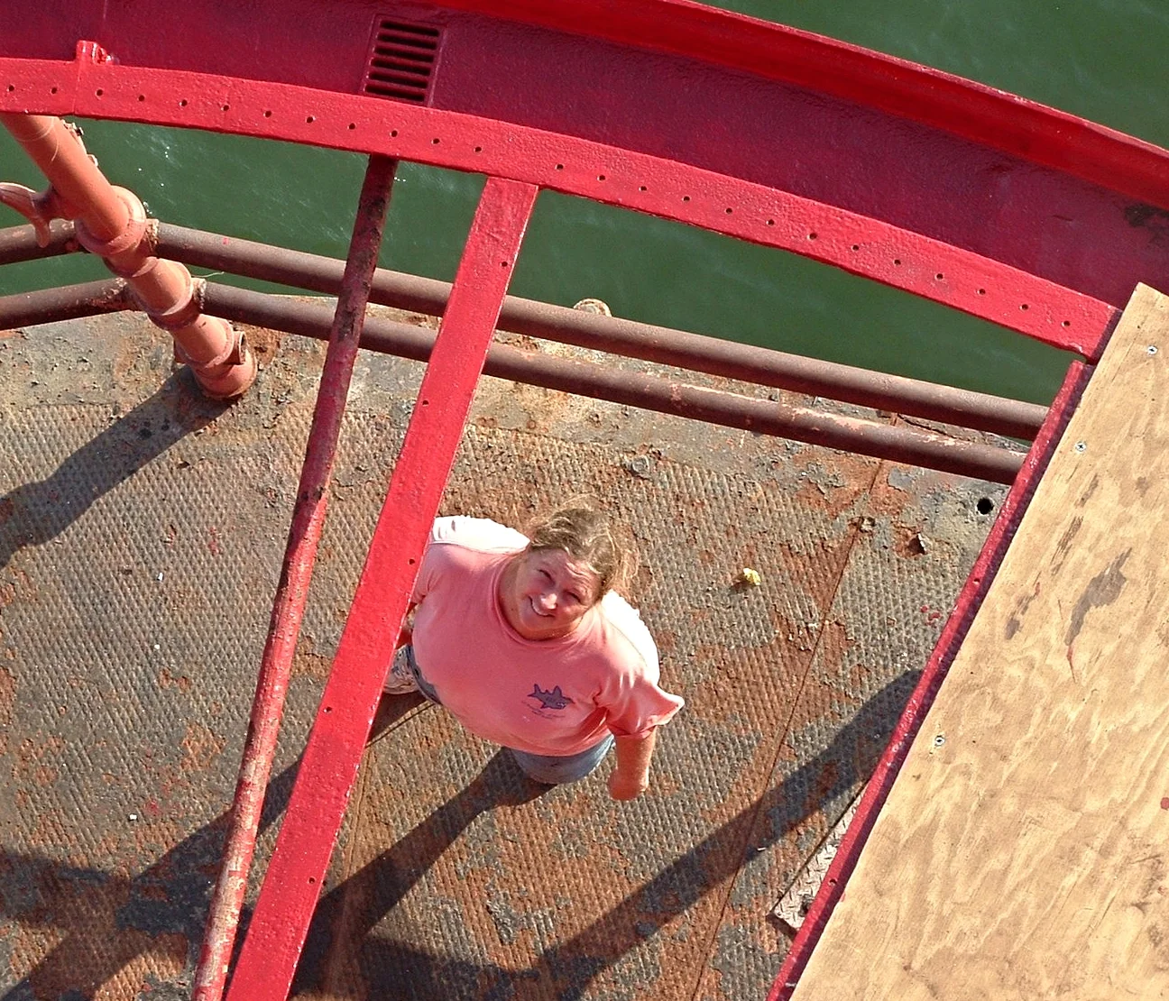 A worker on Middle Ground Lighthouse looking up at the camera through the missing roof during renovation. 