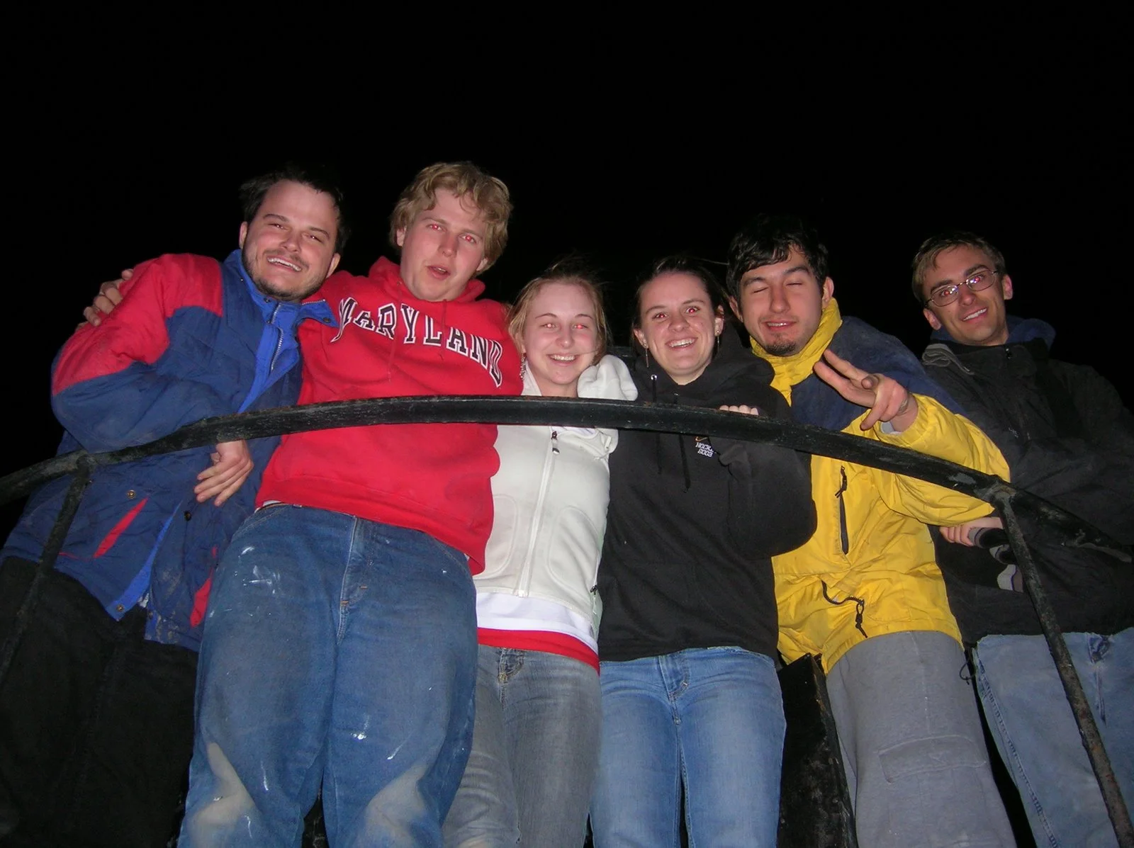 Group of six young adults smiling and posing together at night on Middle Ground Lighthouse.