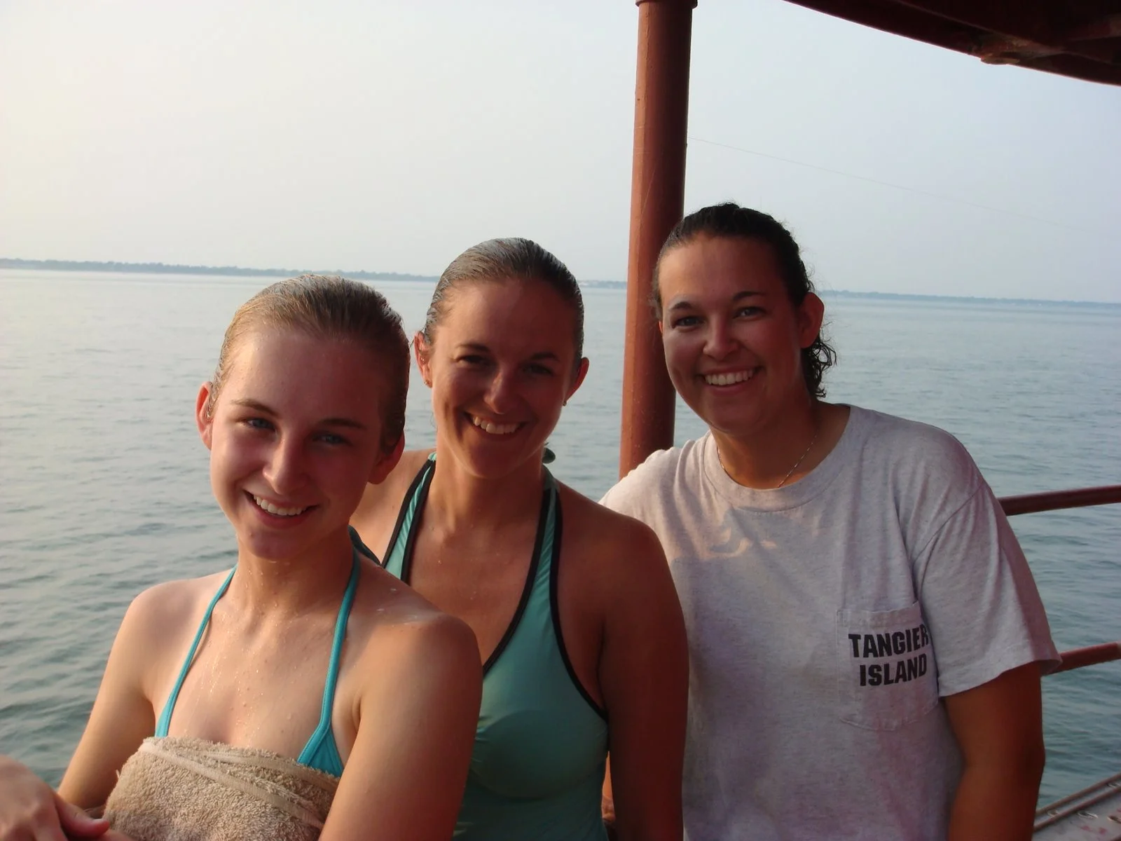 Three women smiling on Middle Ground Lighthouse with water and Hampton Roads in the background