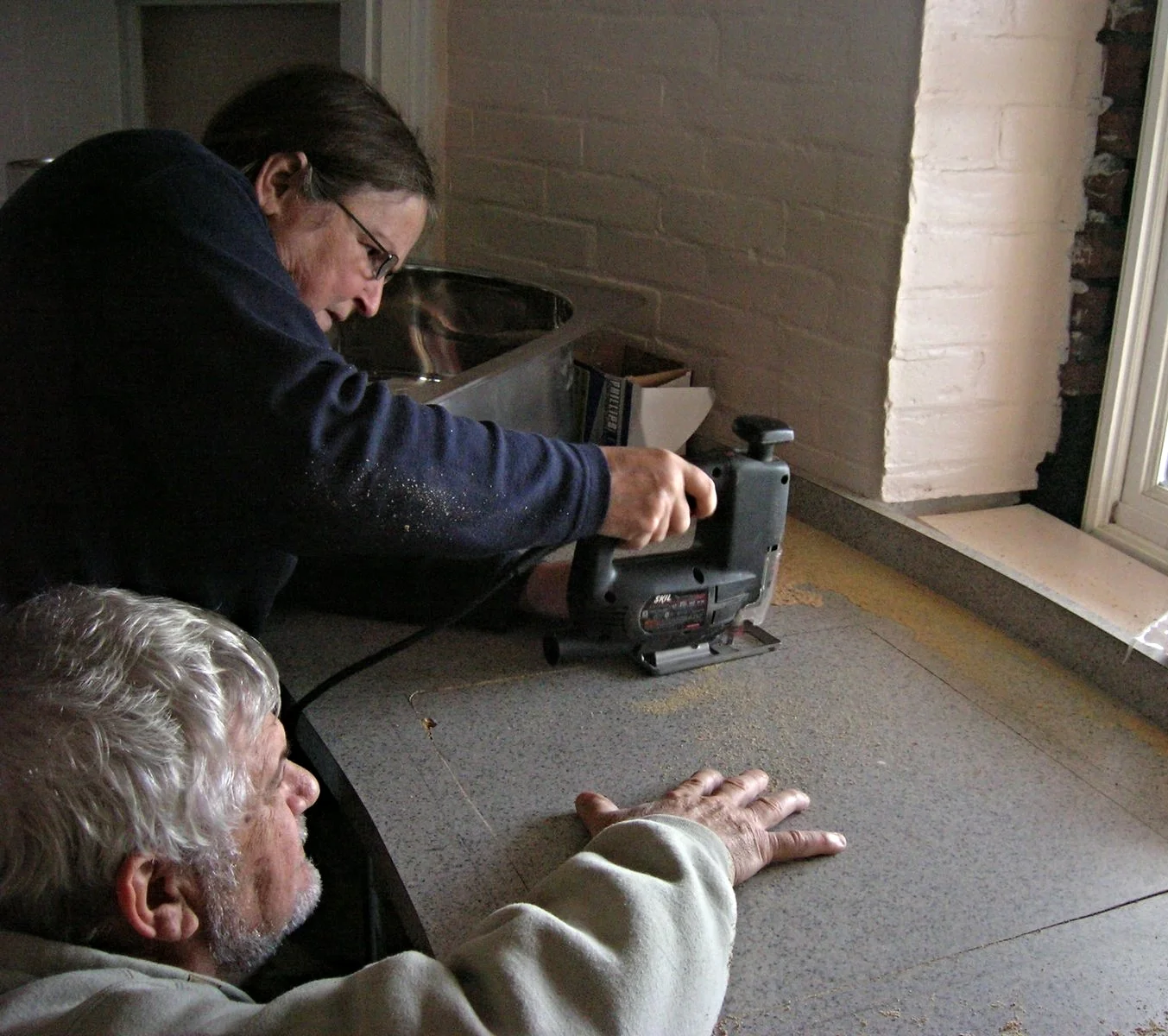 A woman operating a power tool on the kitchen countertop of Middle Ground Lighthouse. 