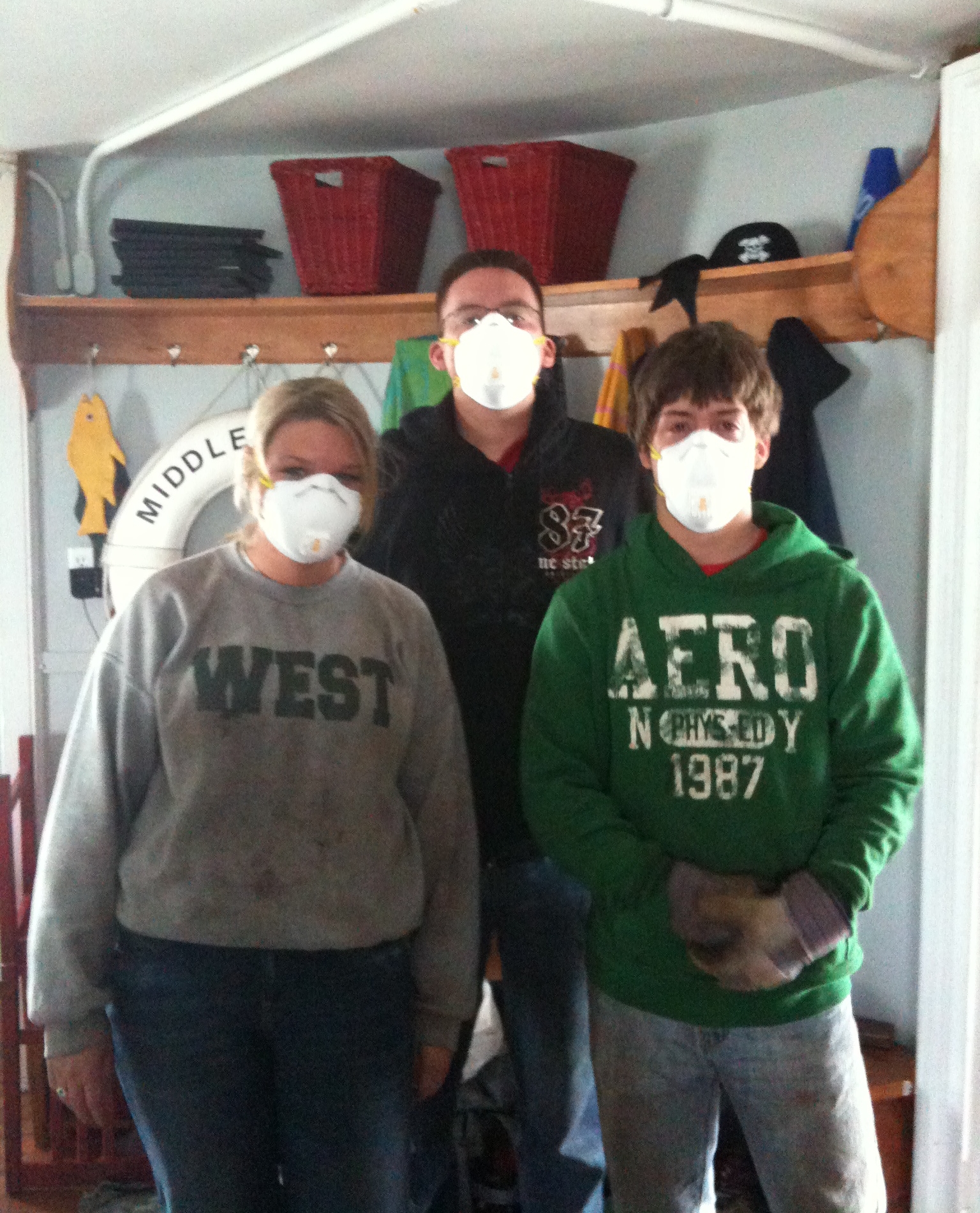 Three individuals wearing face masks are standing in the kitchen of Middle Ground Lighthouse. 