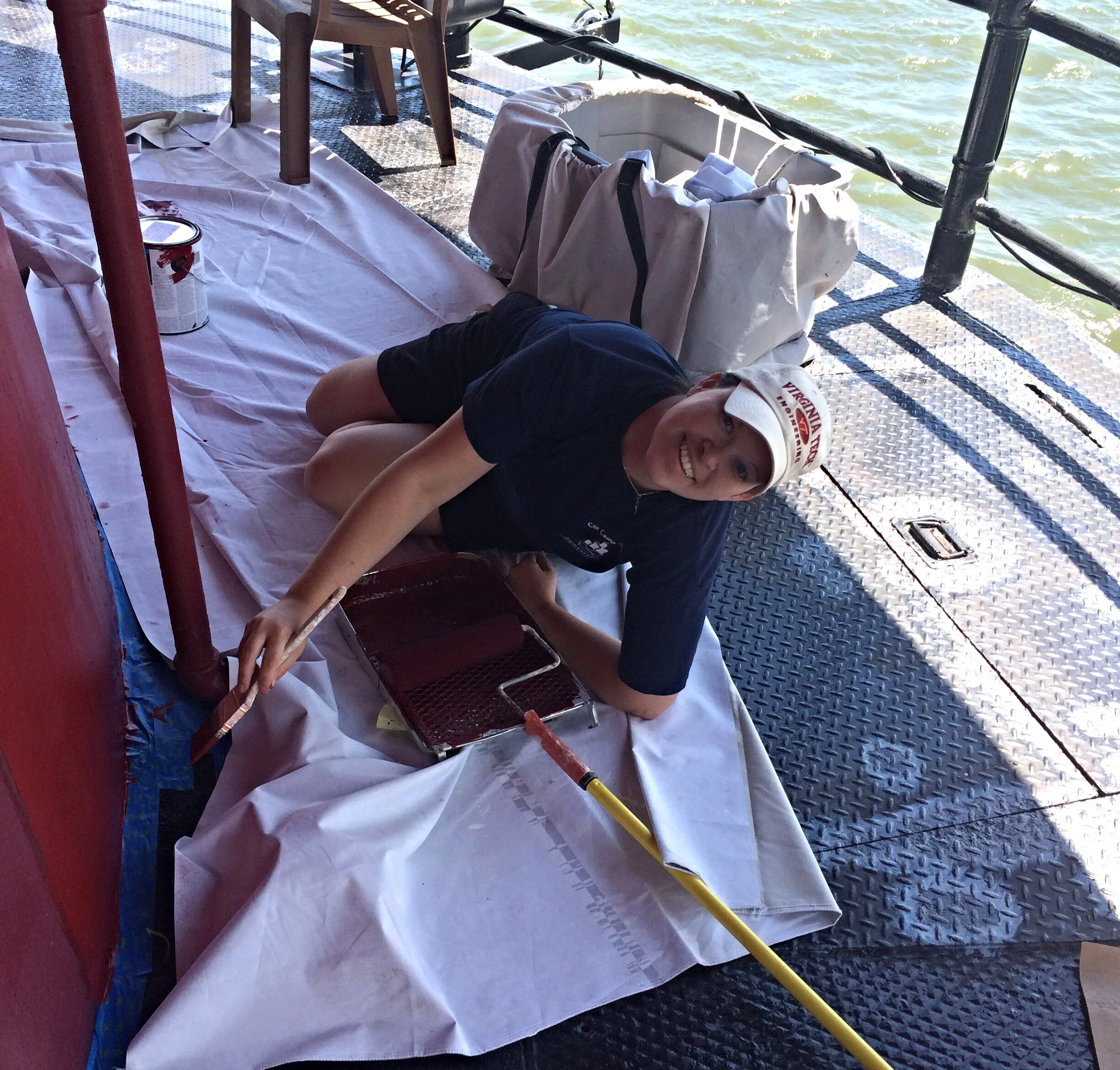 Person lying down on a white cloth on Middle Ground Lighthouse, painting the exterior. 
