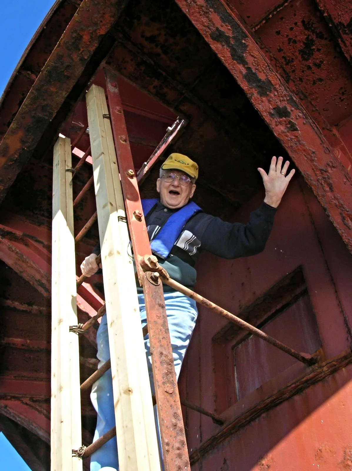An elderly man standing on a rusty metal ladder of Middle Ground Lighthouse. 