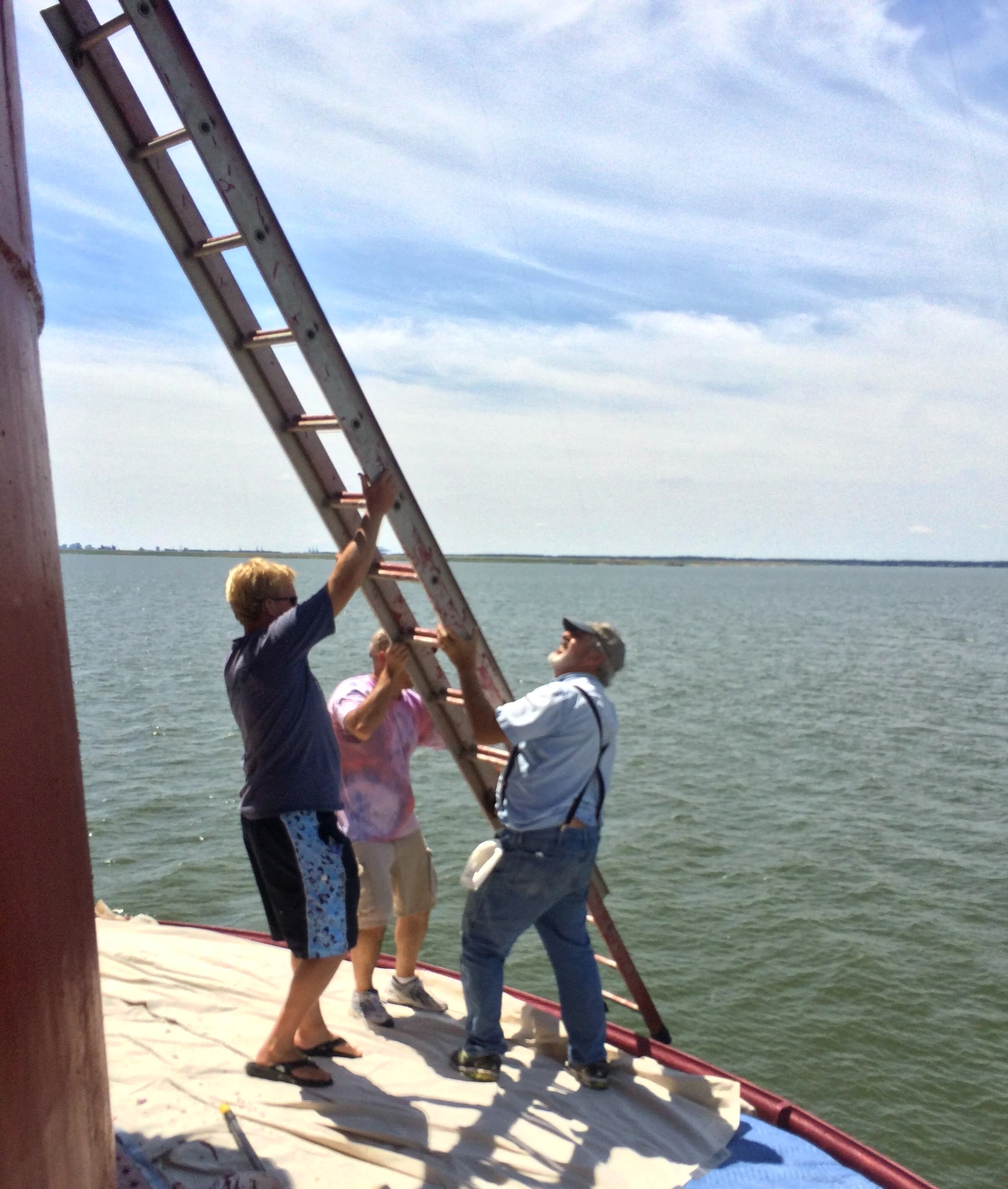 People working together holding a ladder on the roof of Middle Ground Lighthouse. 
