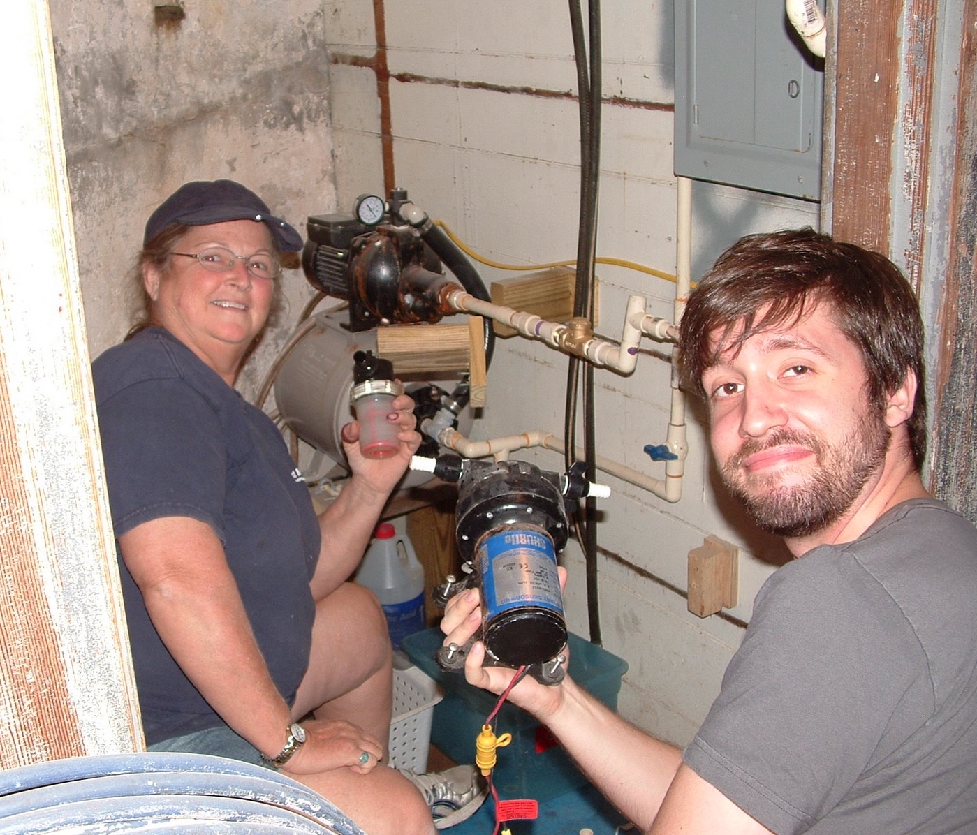A woman and a man working on a water pump system in the cellar of Middle Ground Lighthouse. 