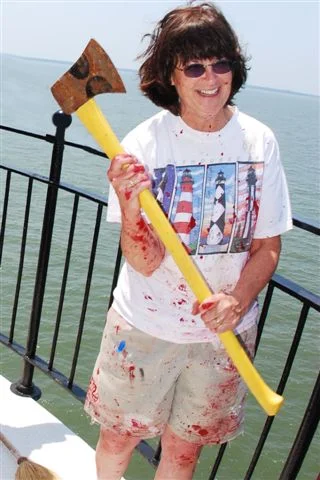 A funny photo of a worker on Middle Ground Lighthouse holding a large axe while covered in red paint.