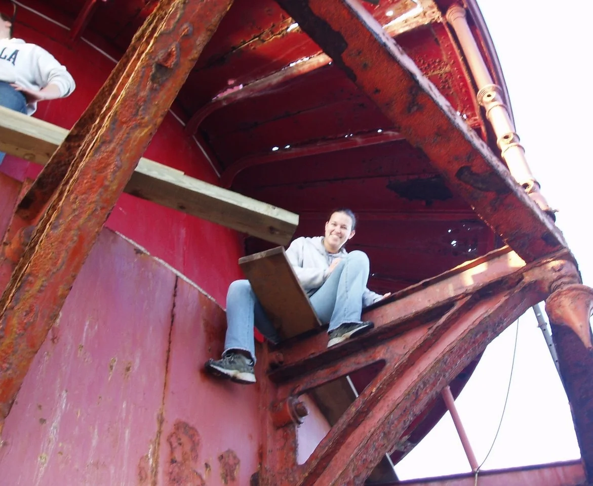 Worker sitting inside a rusty, missing main deck of Middle Ground Lighthouse. 