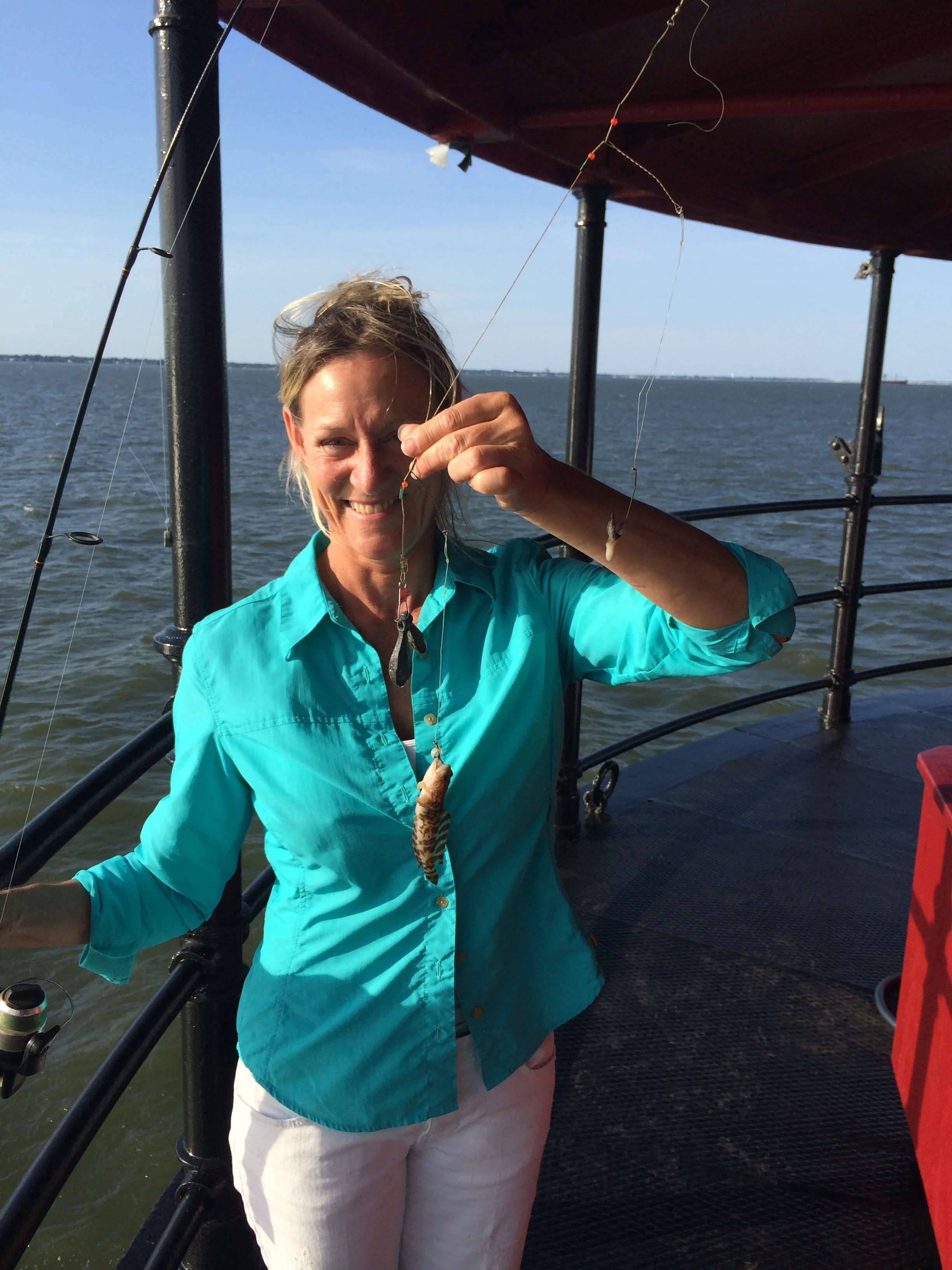Woman on the main deck of Middle Ground Lighthouse holding a small fish she caught.