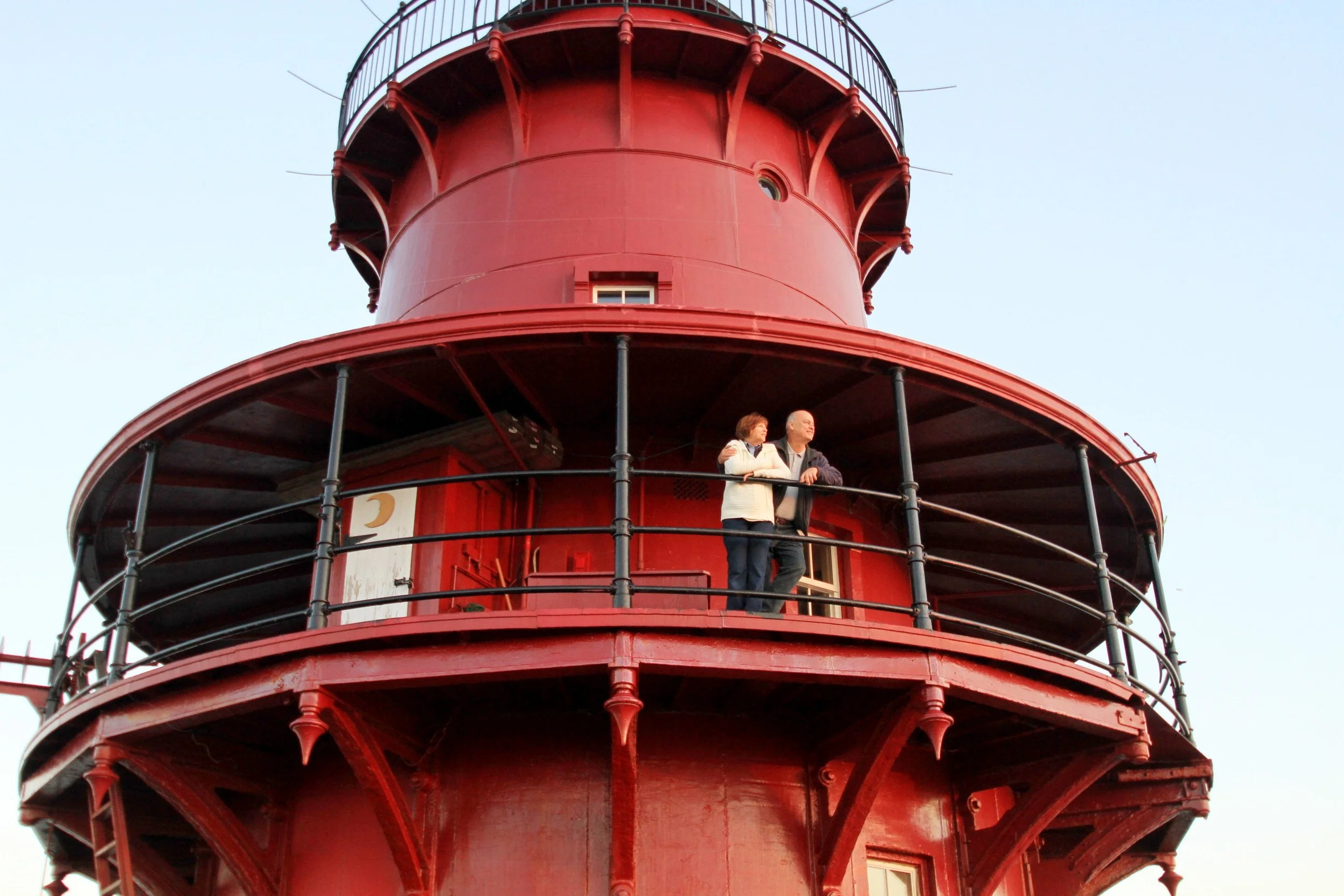 Two people standing on the balcony looking out from Middle Ground Lighthouse. 