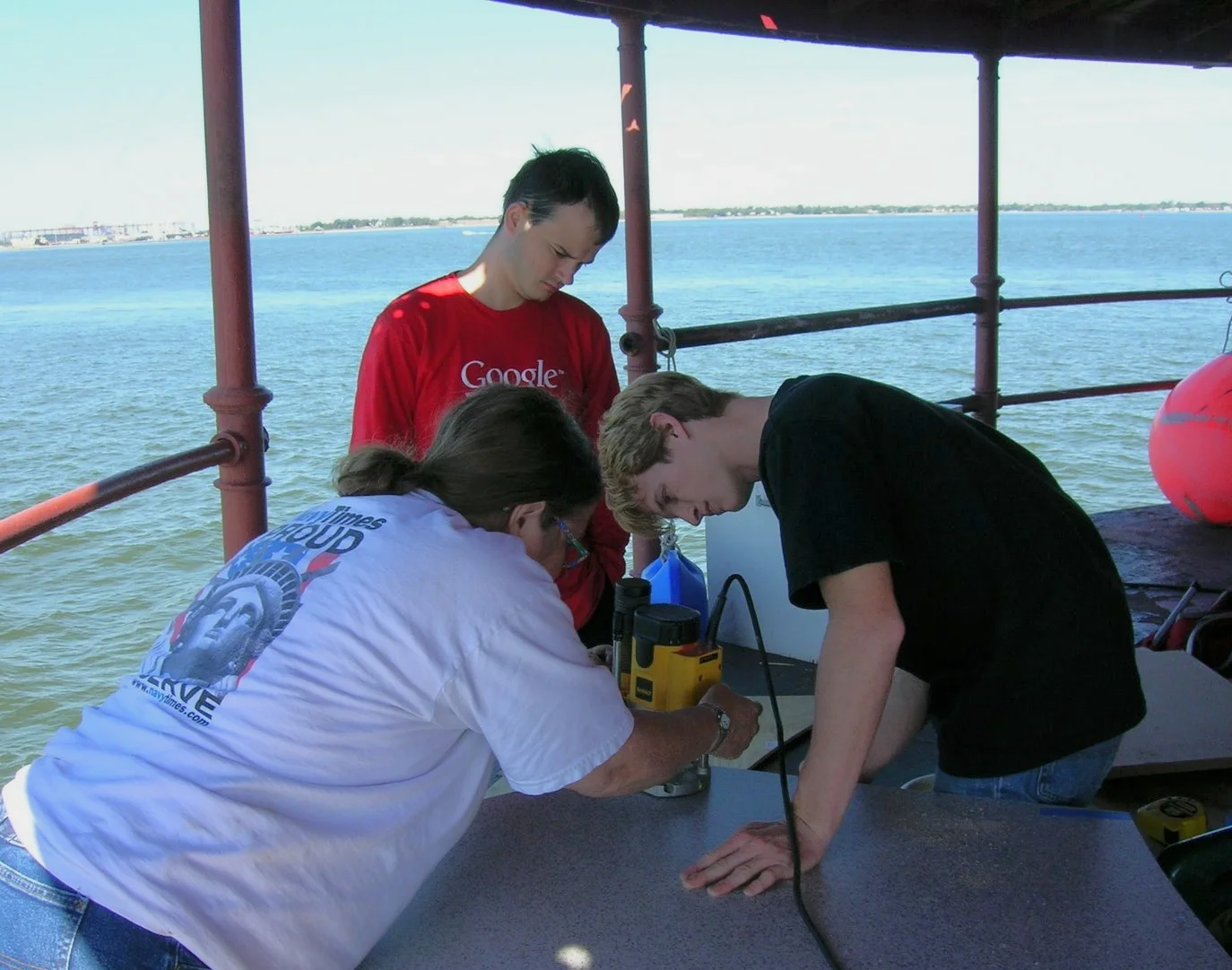 Three people working on the main deck of Middle Ground Lighthouse. 
