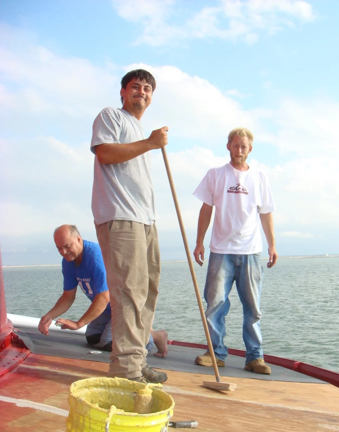 Three men working on the surface of a the main deck roof of Middle Ground Lighthouse. 